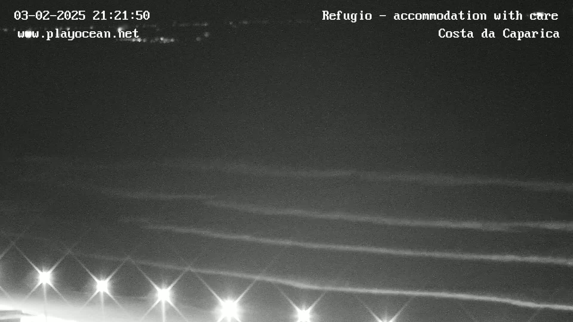 A nighttime long exposure shot shows several horizontal lines of light reflecting on dark water, illuminated by a row of lights along the bottom.