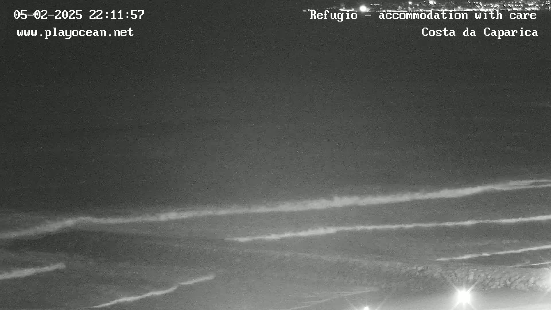 A nighttime long shot shows dark ocean waves rolling onto a shore under a clear, dark sky.