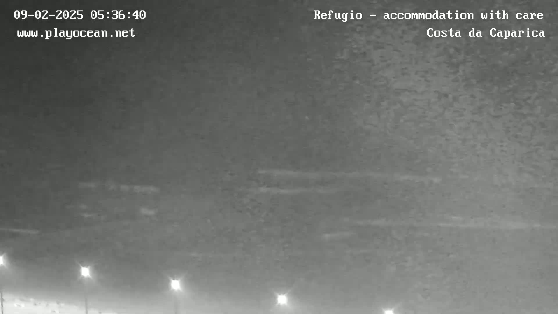 A nighttime, overcast view shows a flat, dark landscape illuminated by a few distant lights.