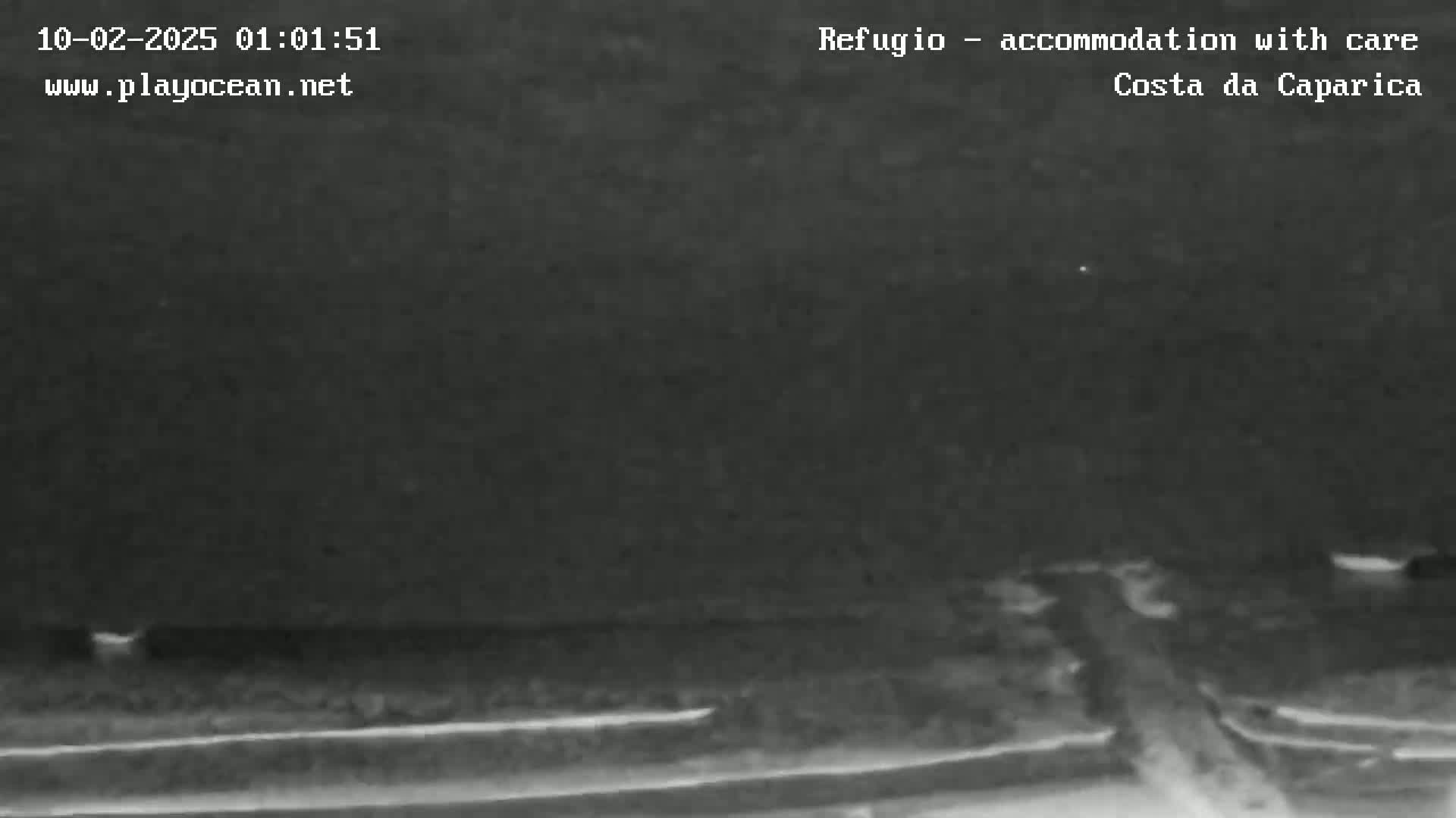 A nighttime, low-light image shows a dark, flat landscape with a road or path cutting through it.