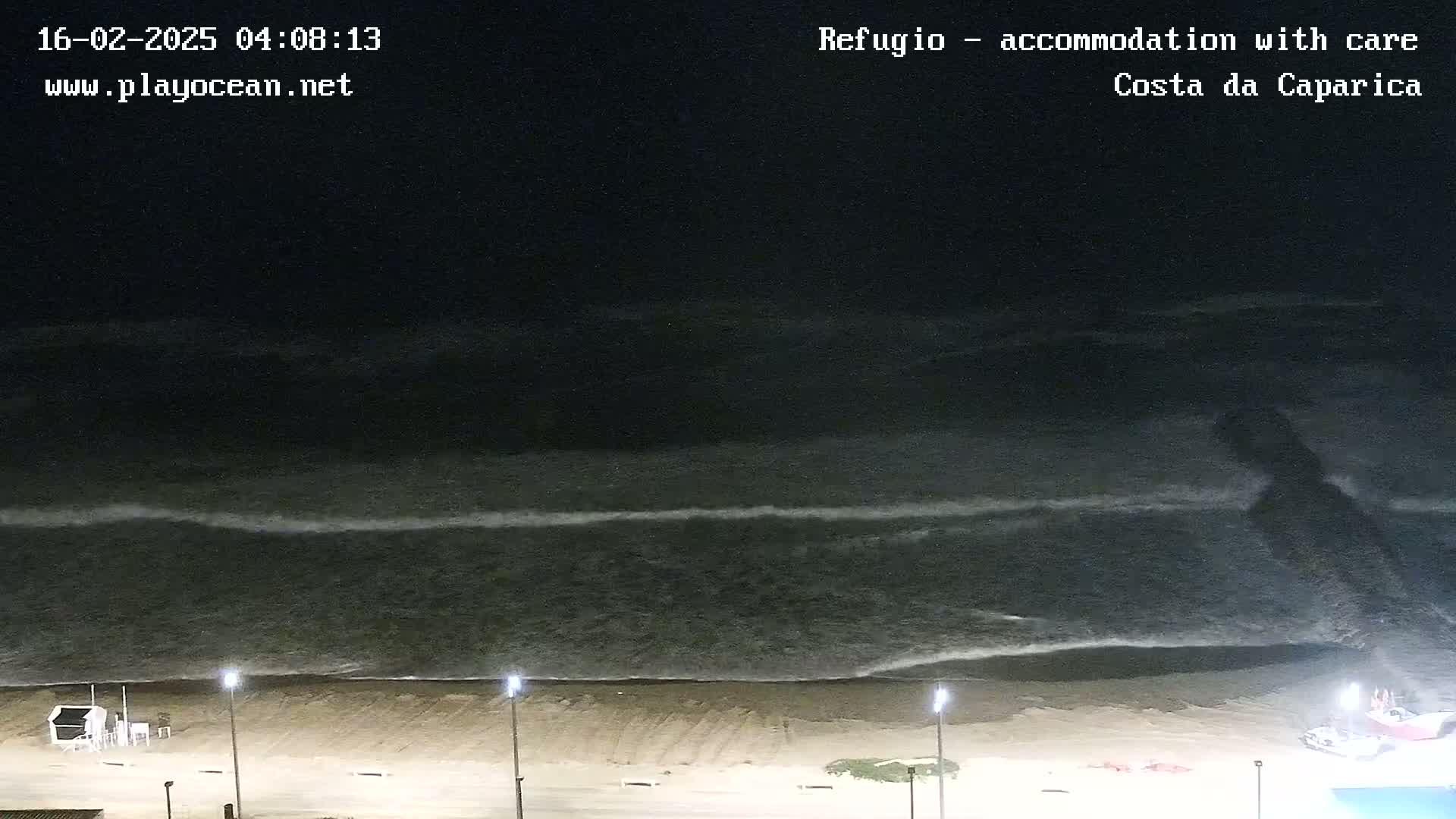 At night, gently rolling waves lap a sandy beach under a dark sky.