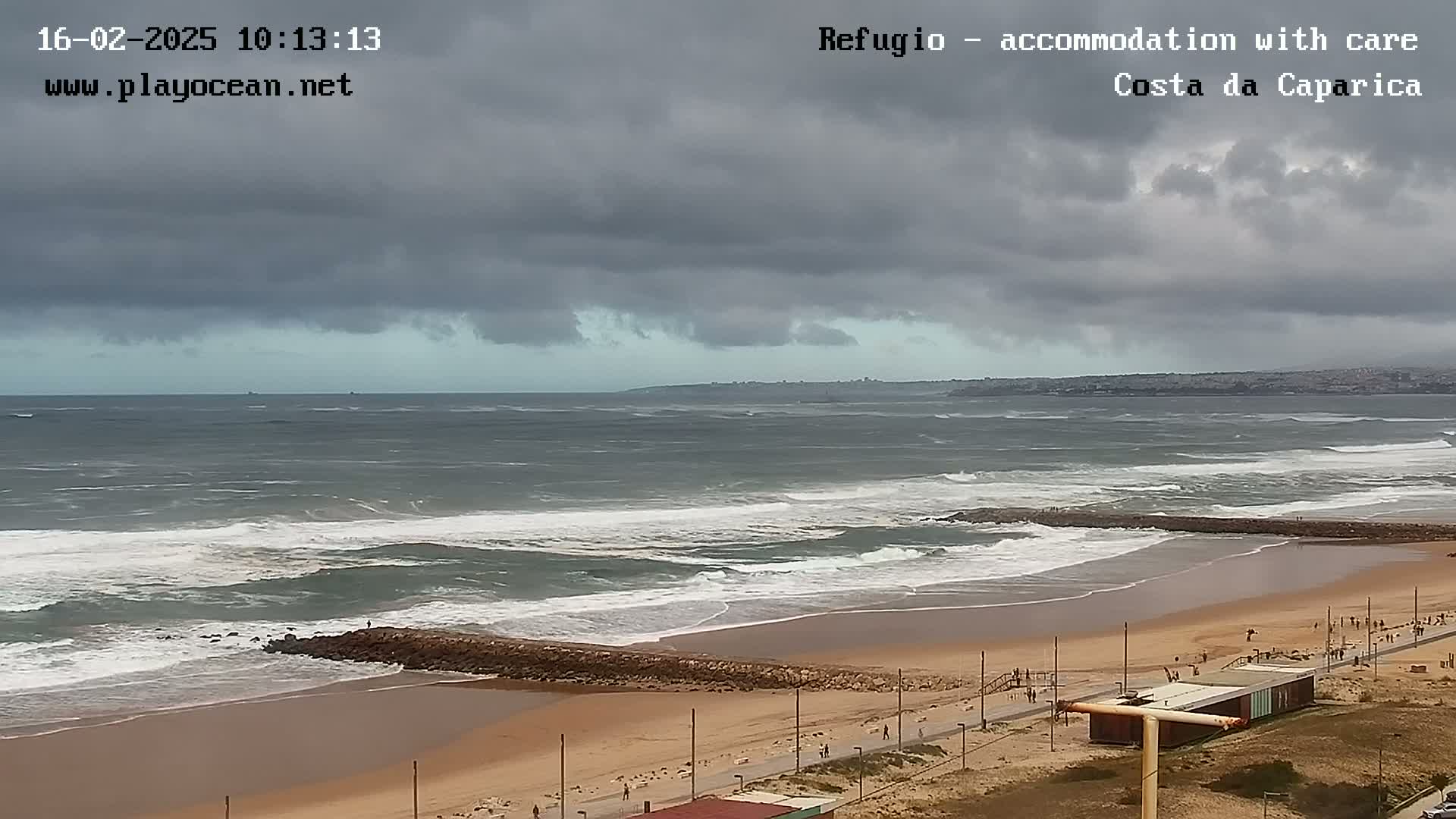 A wide shot of a beach with waves under a cloudy sky.