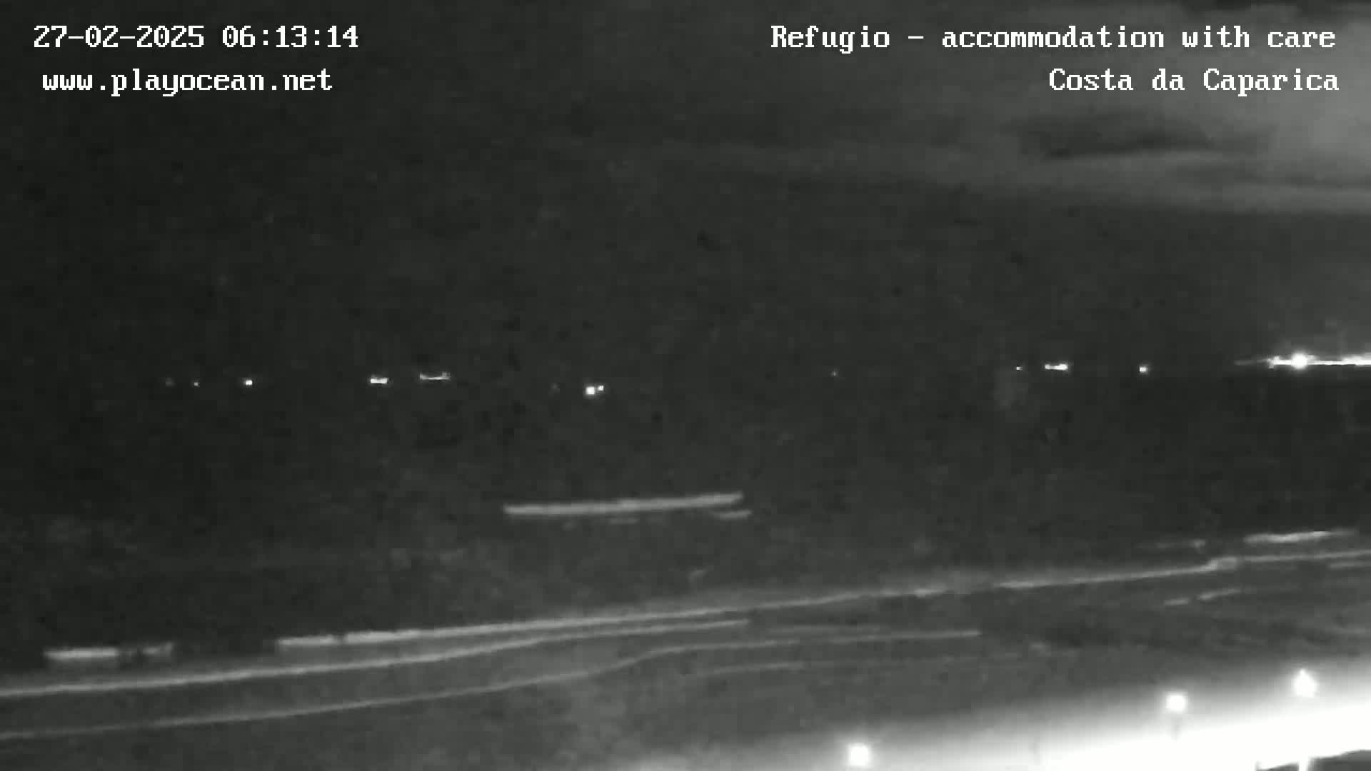A nighttime, low-light view shows a dark landscape with a few distant lights and a road in the foreground.