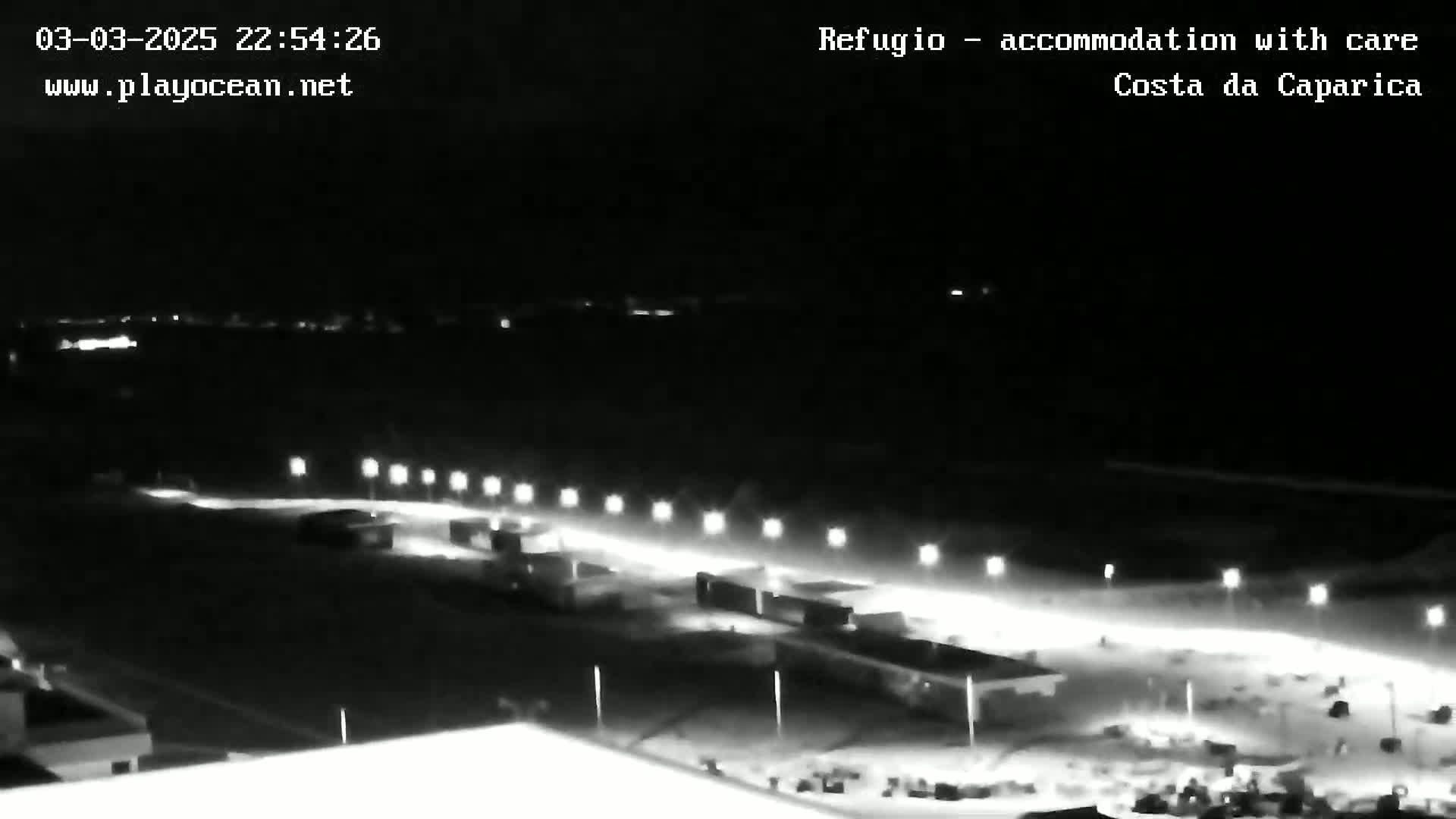 A nighttime, long shot of a brightly lit road and surrounding area, possibly a parking lot or other outdoor space.