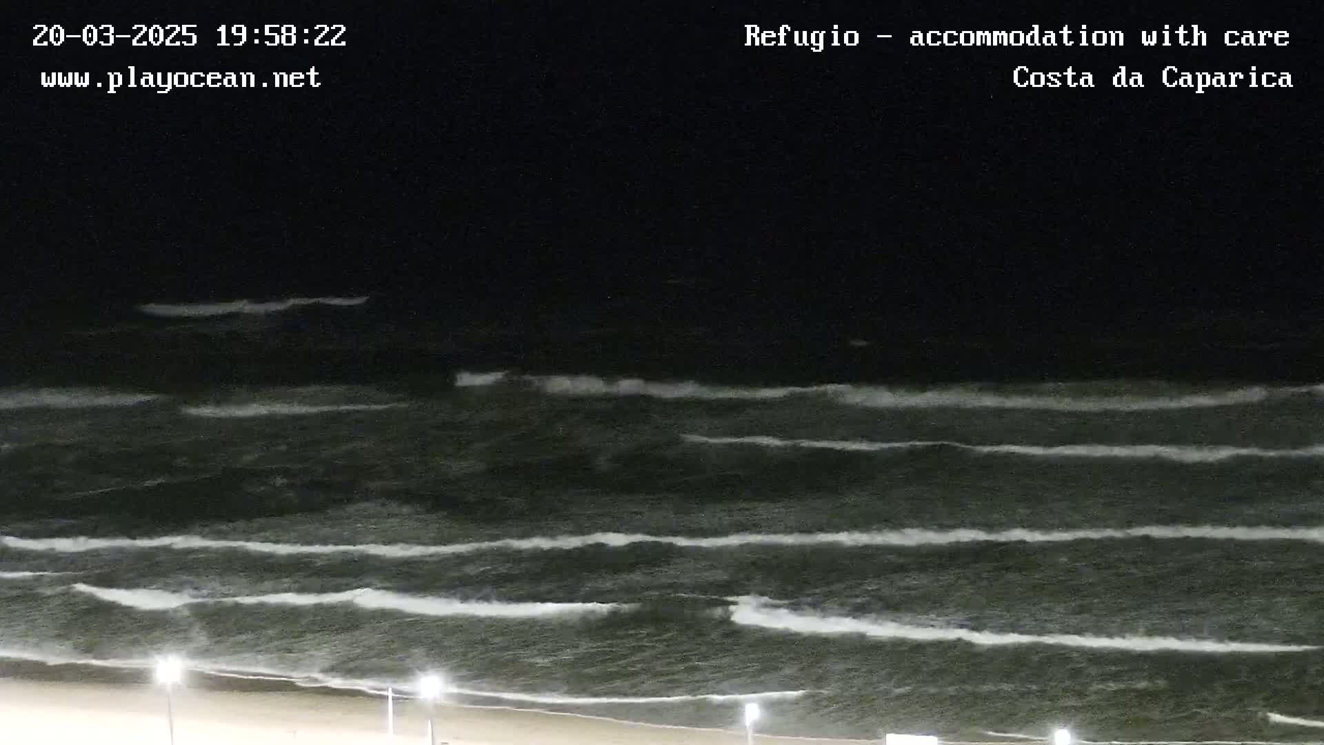 Dark waves roll onto a beach at night.