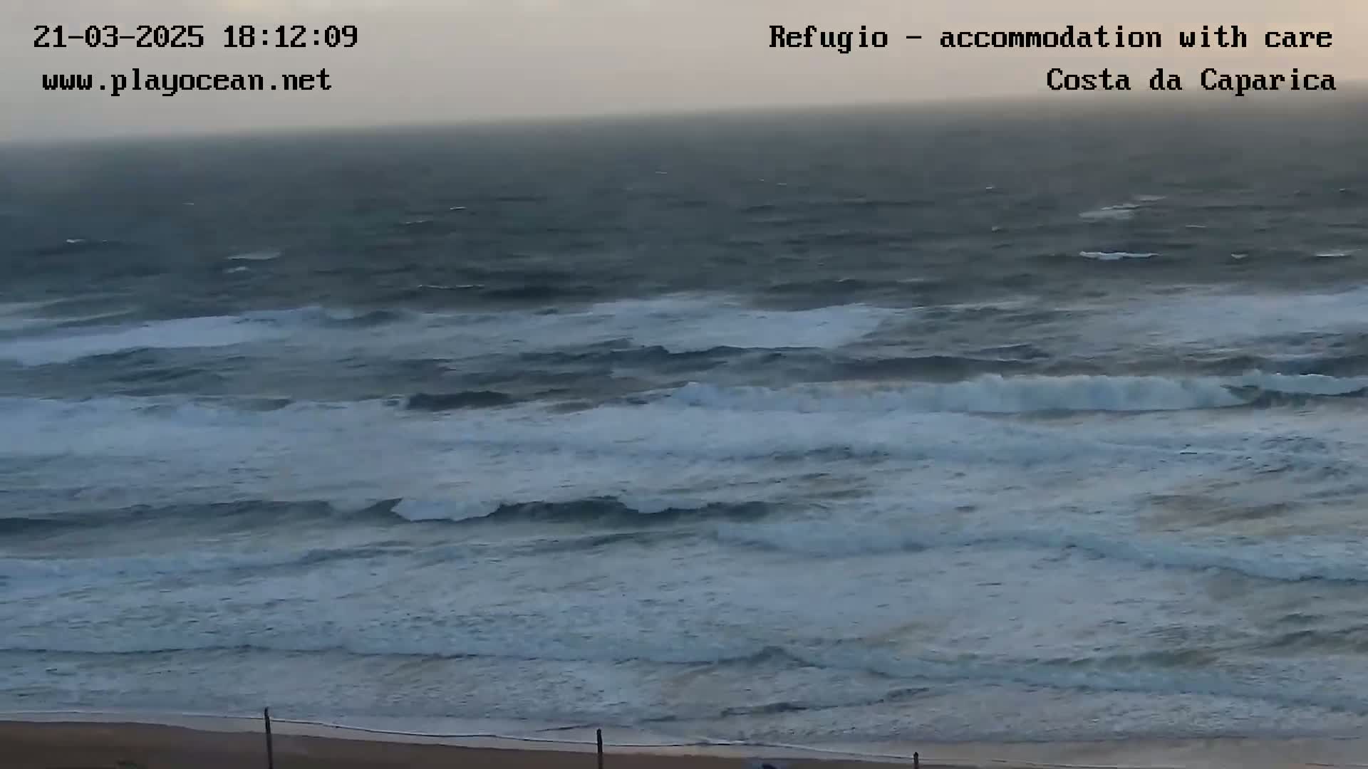A wide shot shows a beach with a choppy, gray ocean under an overcast sky.