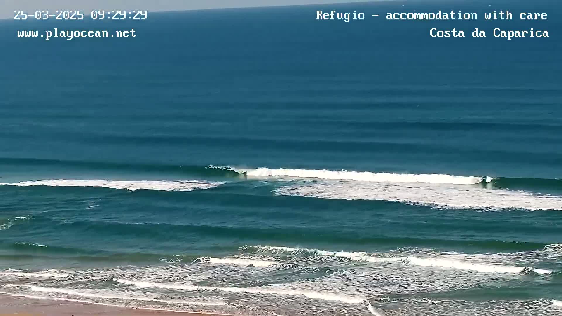 Ocean waves roll onto a sandy beach on a sunny day.