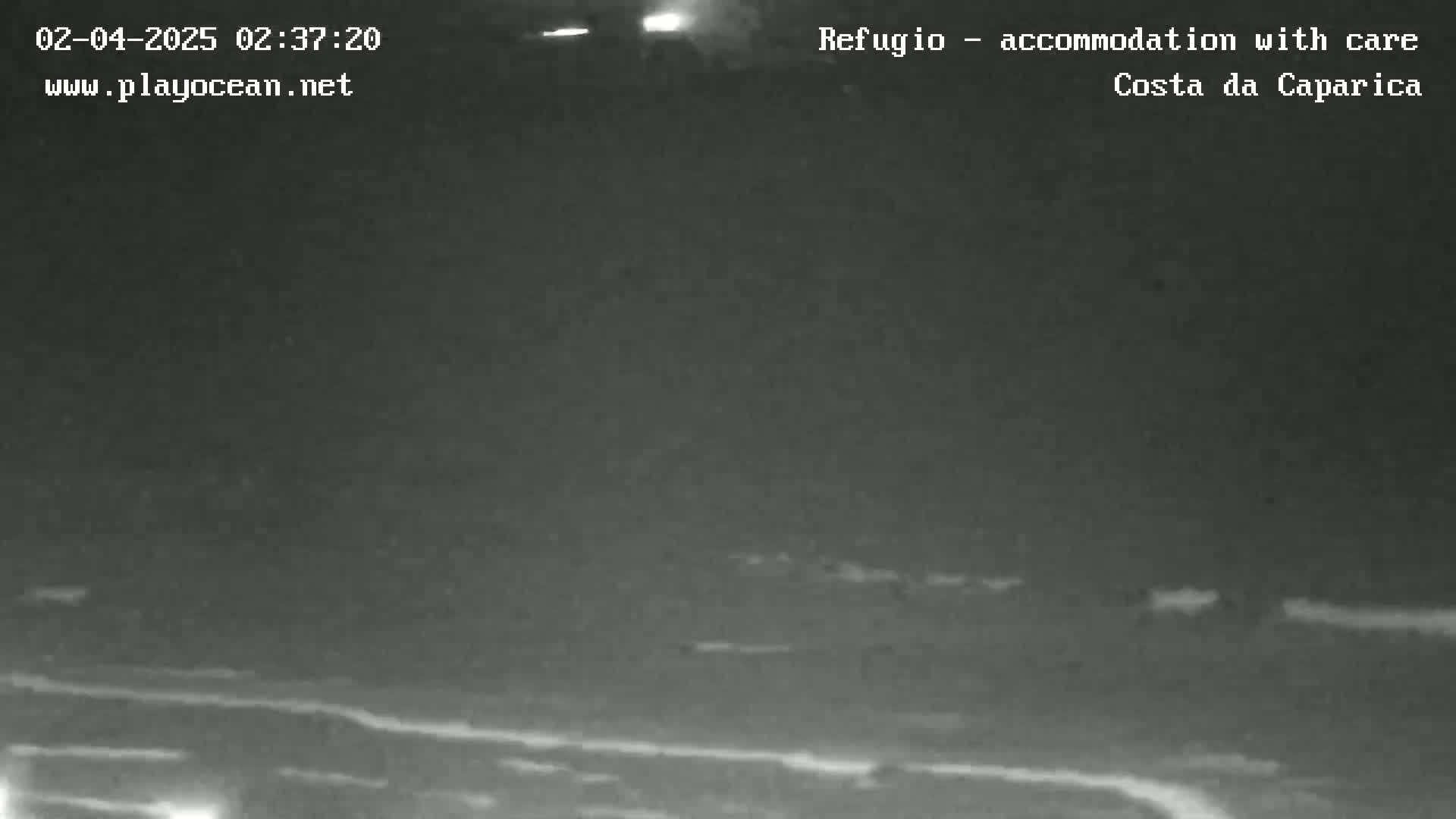 A nighttime, low-light view shows dark water with faint white lines possibly indicating waves or reflections under a dark, overcast sky.