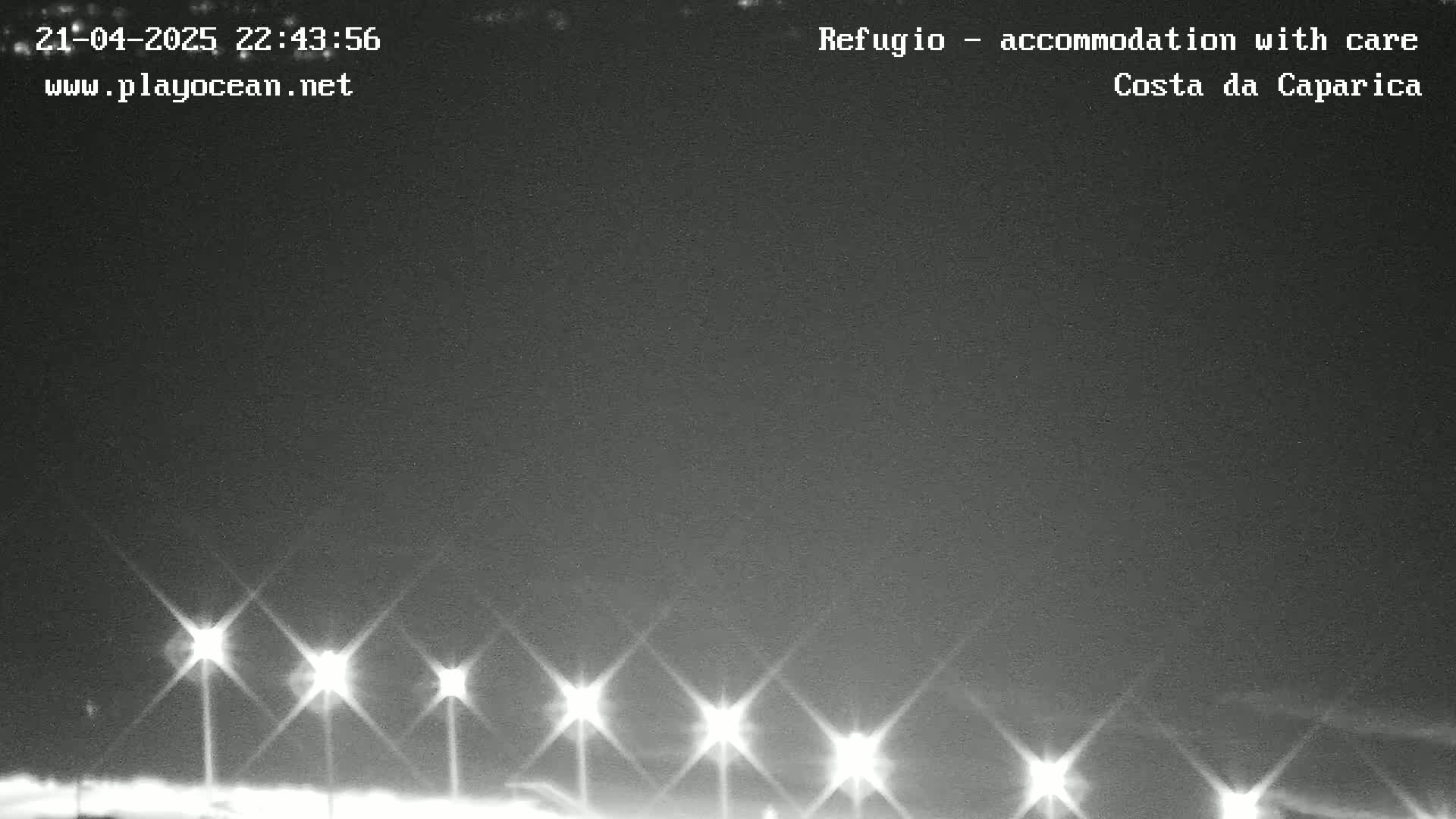 A nighttime, low-light view of several bright lights illuminating a dark, mostly clear sky.