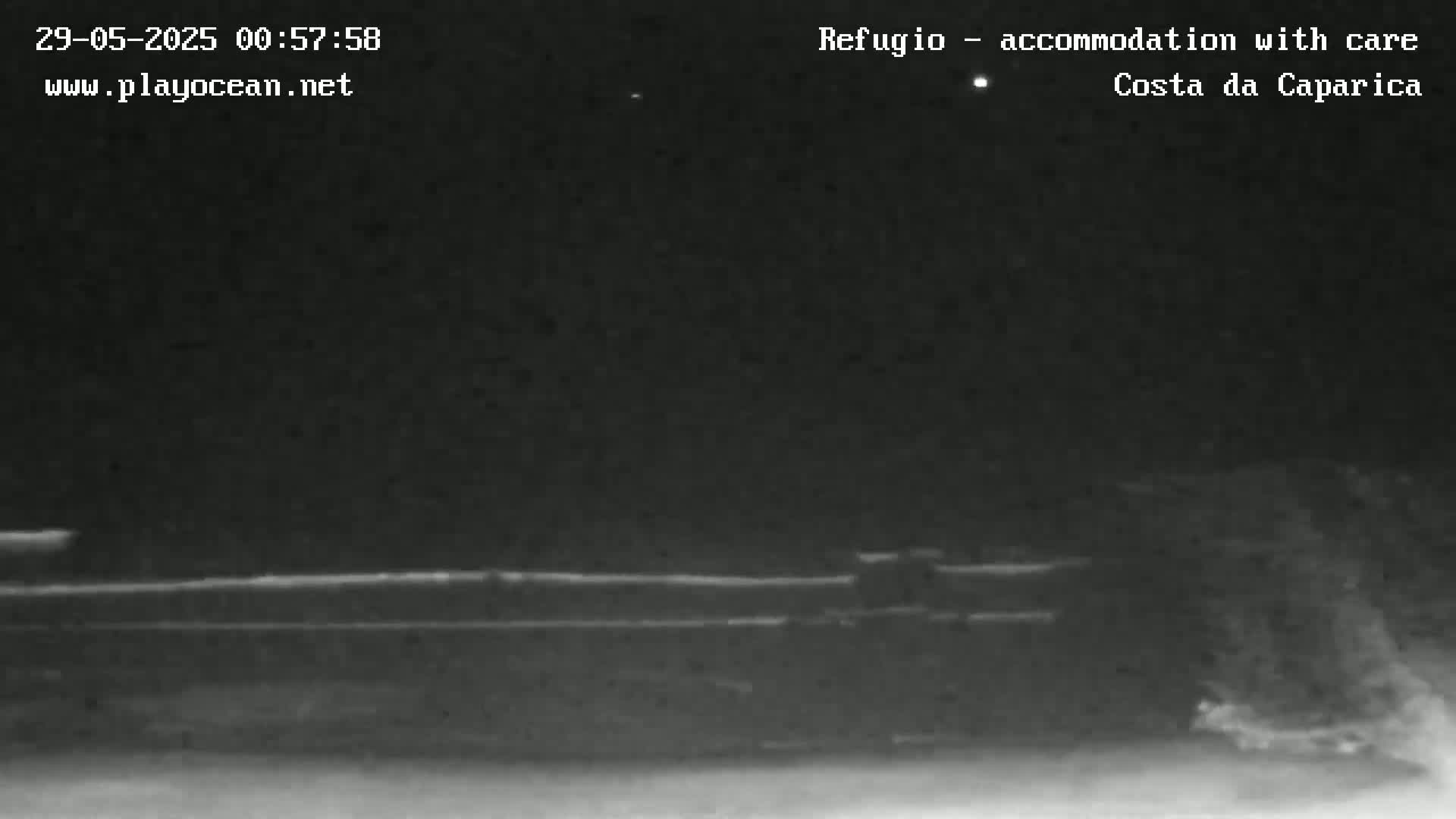 A nighttime, low-light image shows a dark, flat landscape under a clear sky with a few visible stars.
