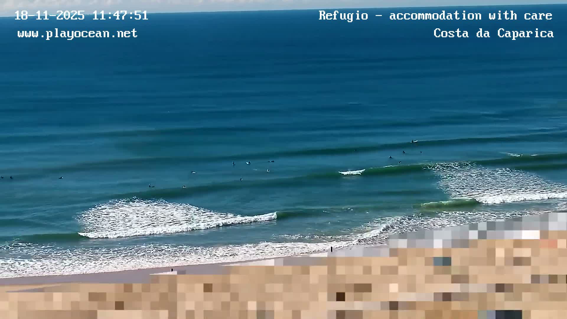 A nighttime, beachside view shows a row of lights illuminating a sandy beach and ocean waves under a dark sky.