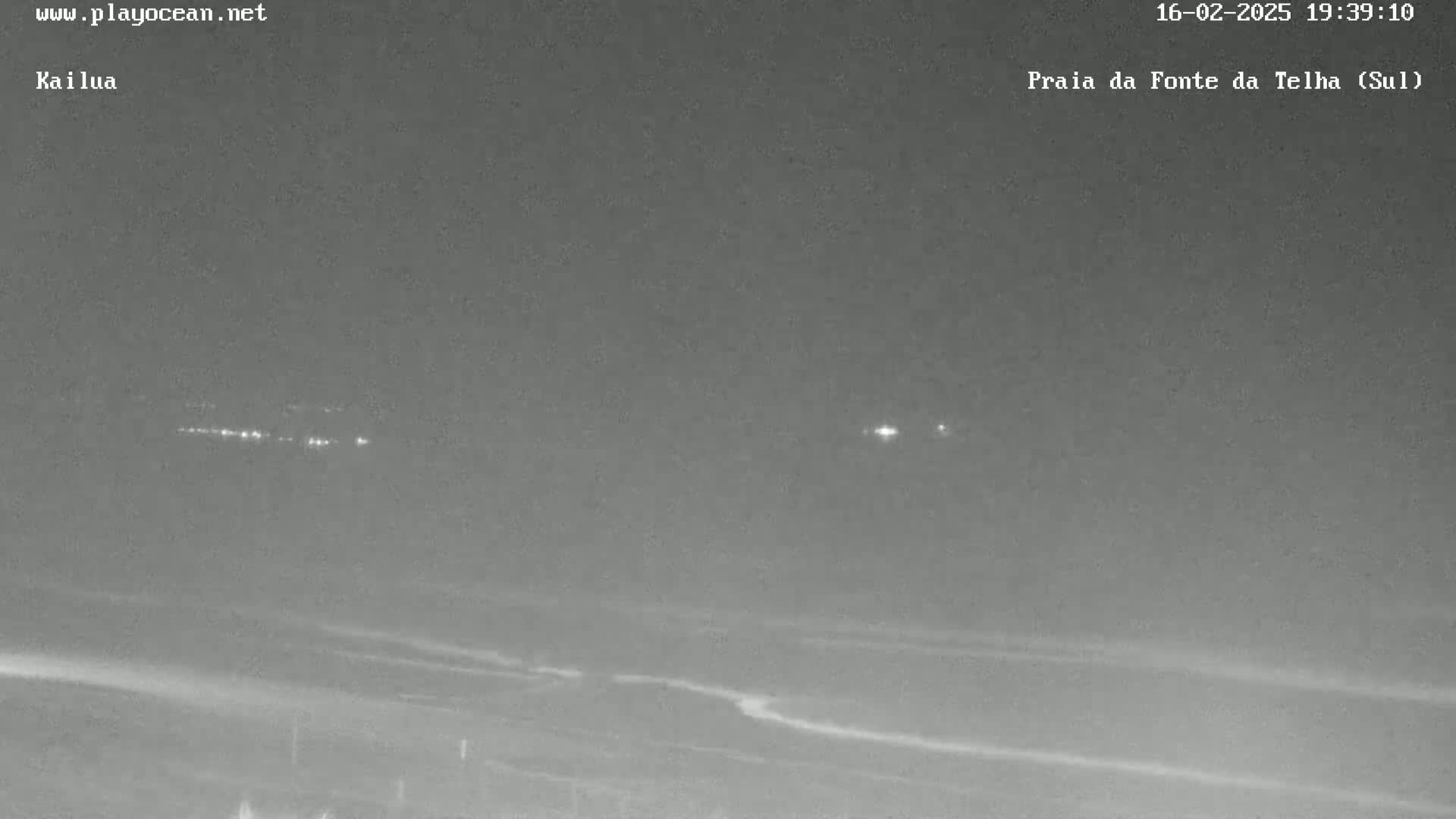 A nighttime long shot shows a dark beach with distant lights and a mostly clear sky.