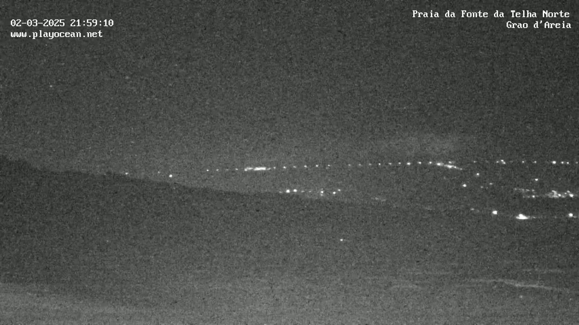 A nighttime, long-range view of a distant town's lights spread across a dark landscape.