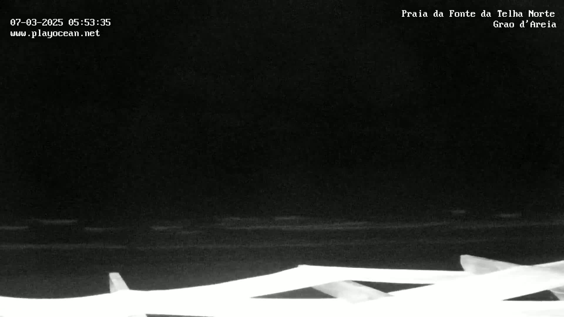A nighttime, low-light view of a dark body of water with a partially visible white structure in the foreground.