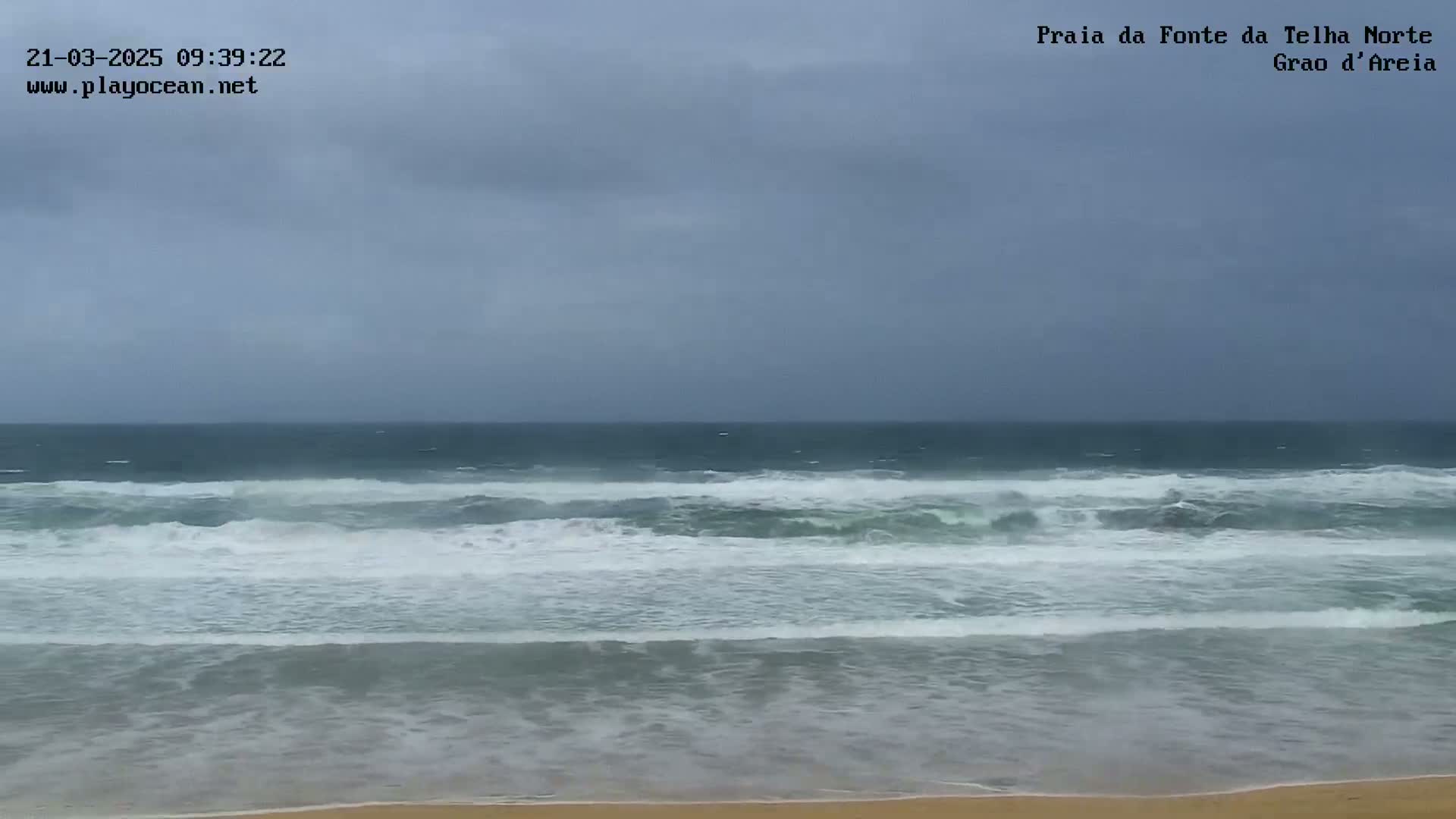 A beach with moderate waves under an overcast sky.