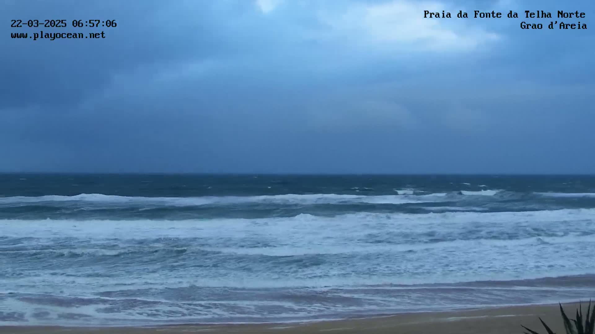 A beach with choppy, dark-blue waves under an overcast sky.