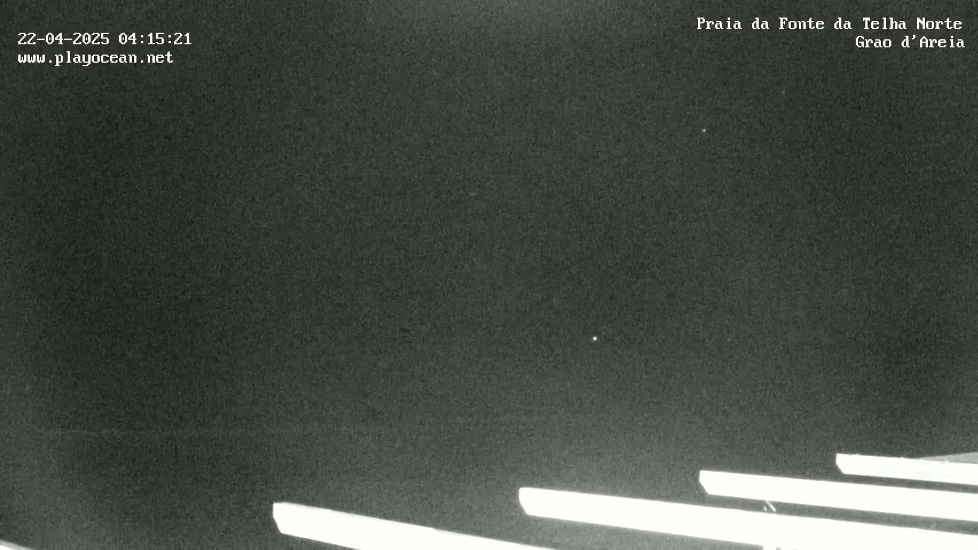 A nighttime, low-light outdoor image shows several long, horizontal, bright lines at the bottom of the frame against a dark sky.