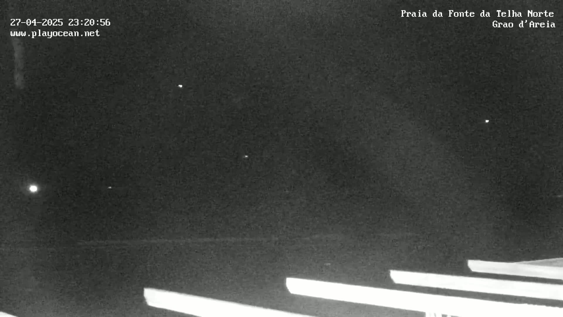 Under a dark, clear night sky, several bright lights are visible above long, horizontal, light-colored lines on the ground.