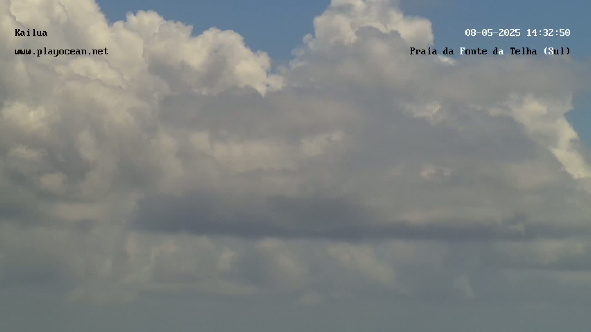 A mostly cloudy sky fills the frame, with puffy white and gray clouds dominating the view.