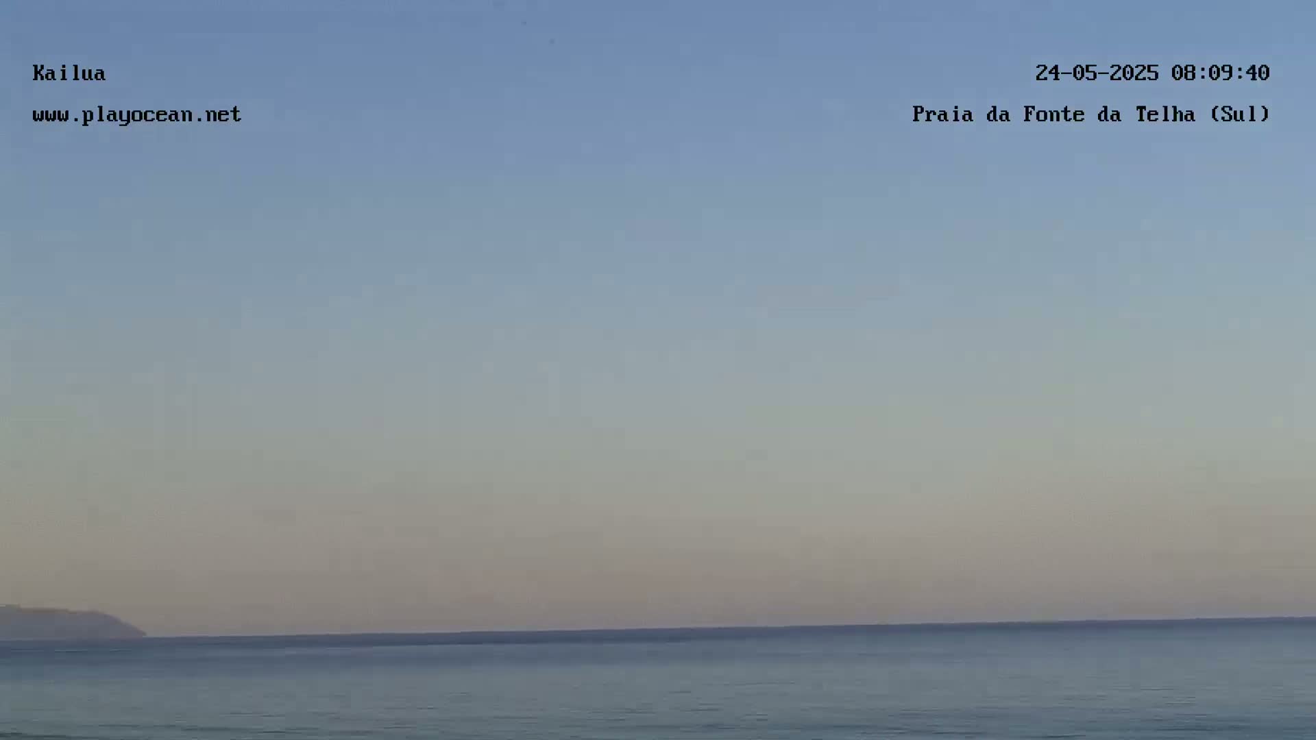 A calm ocean meets a pale, clear sky under a soft, light-colored dawn.