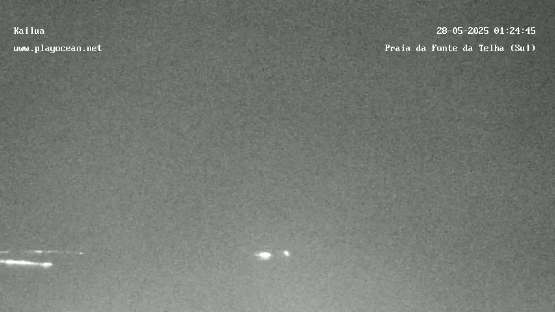 A nighttime, low-light image shows a dark gray sky with a few faint lights visible near the horizon.
