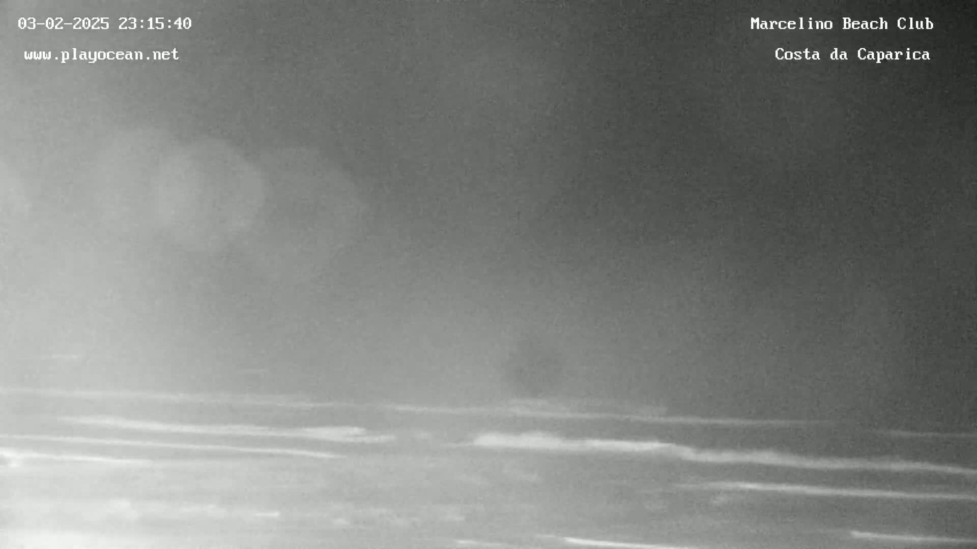 A nighttime, low-light image shows a dark, somewhat hazy ocean with small waves under a dark sky.