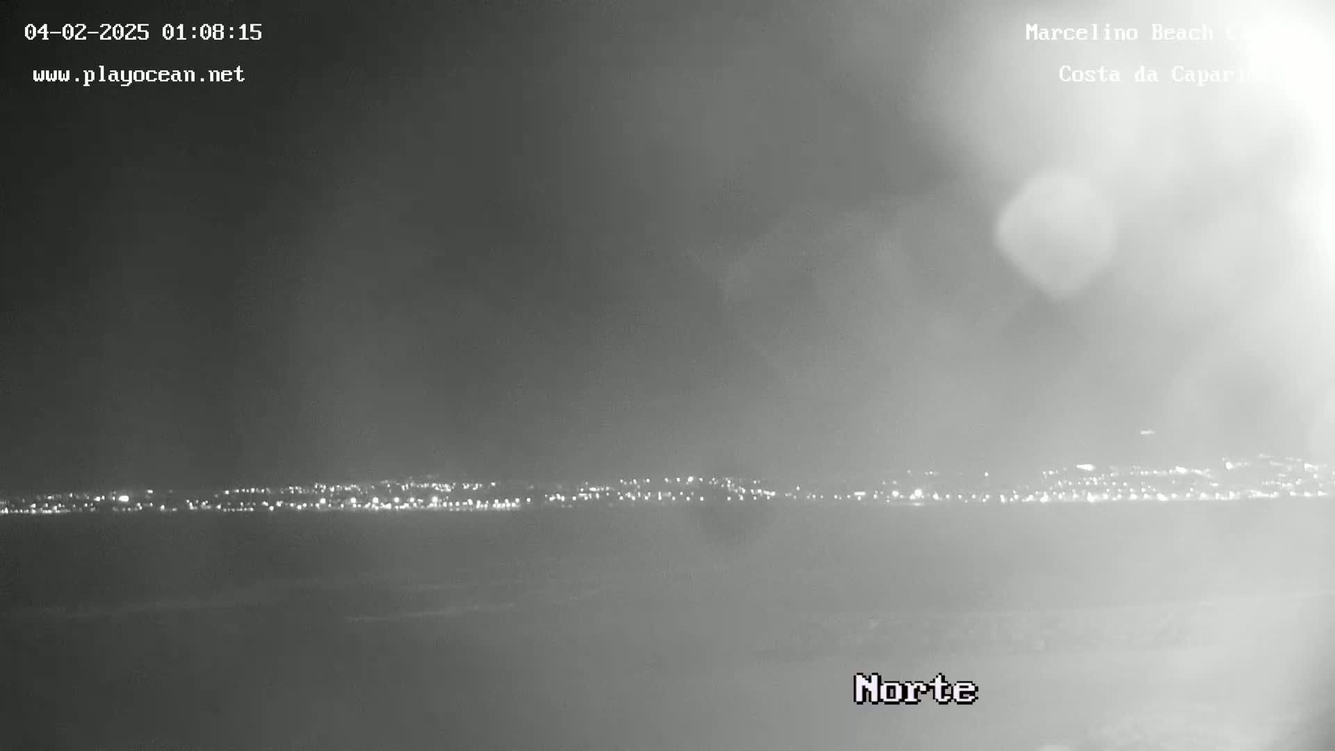 A nighttime, hazy view of a distant city skyline illuminated by lights.