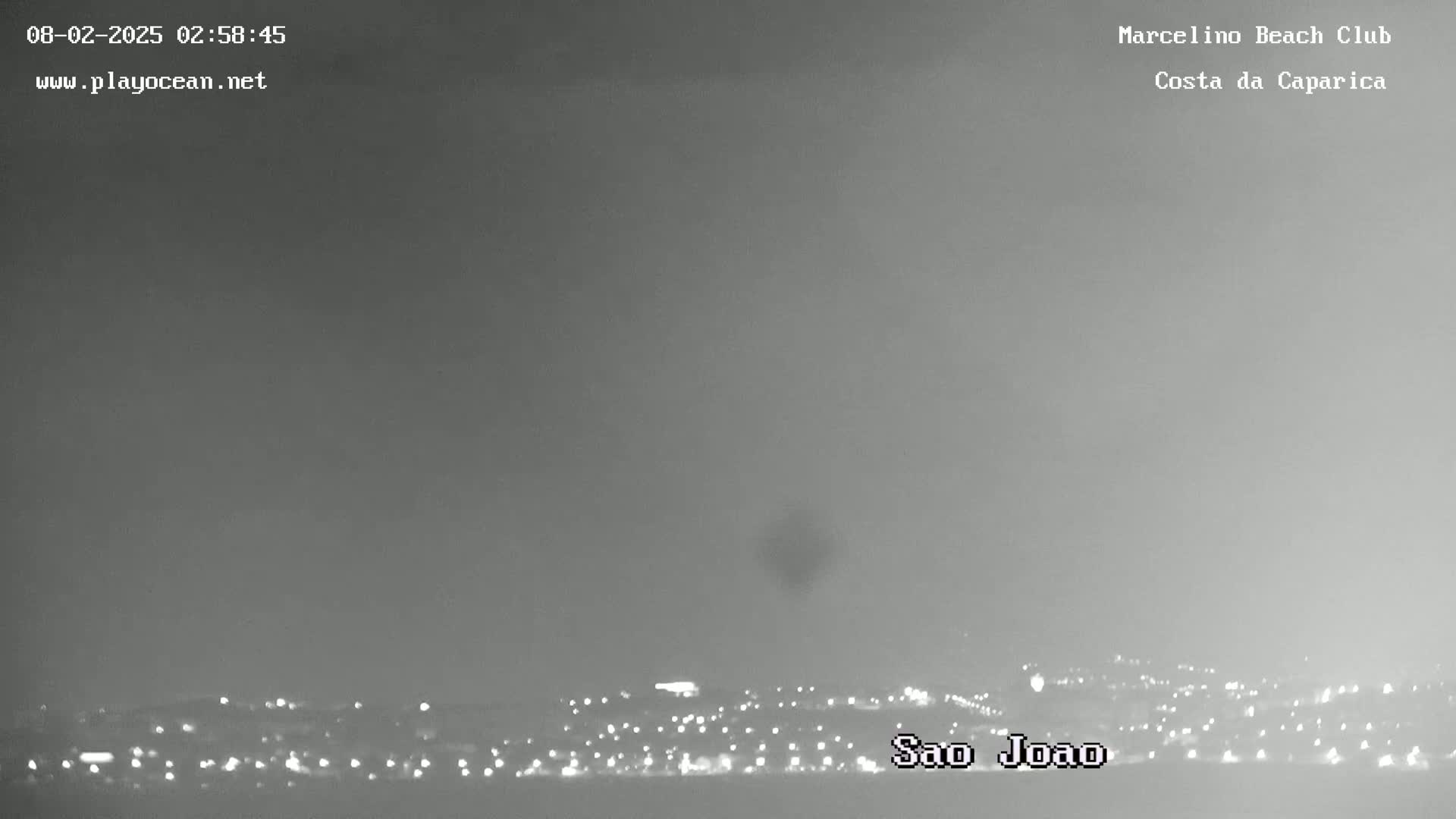 A nighttime long shot shows a hazy, dark cityscape with many small lights, possibly under a foggy or overcast sky.