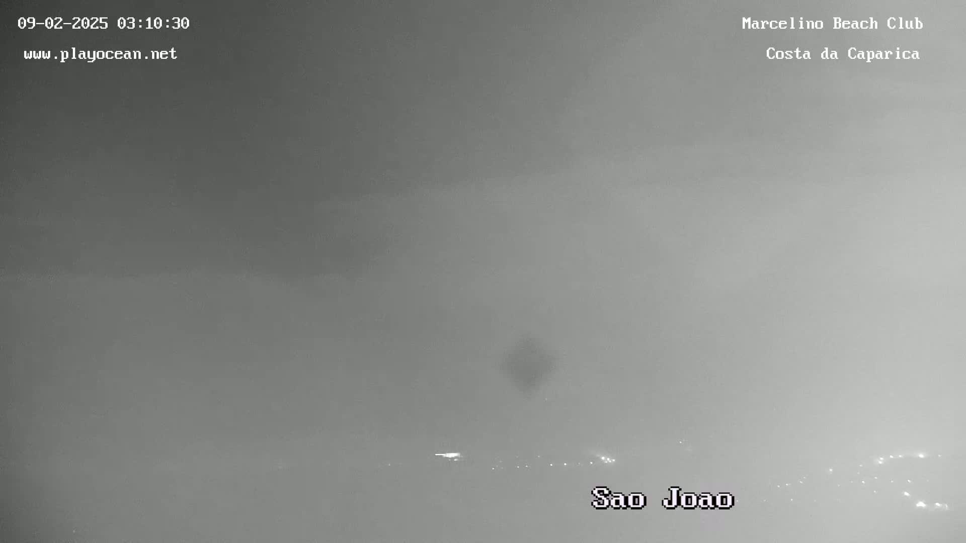 A hazy, overcast view shows a distant line of lights at the horizon.