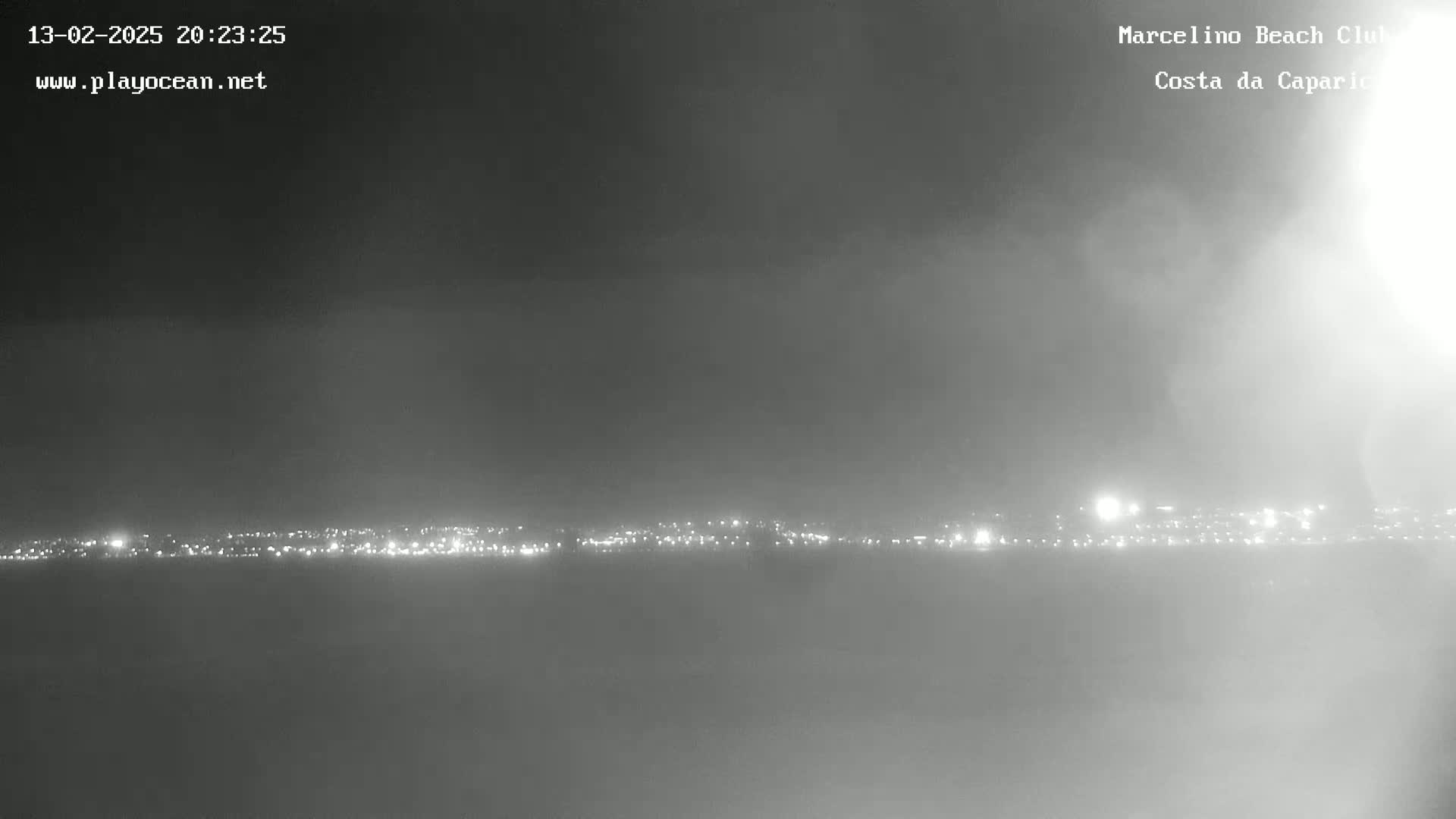 A hazy night scene shows a distant line of city lights.