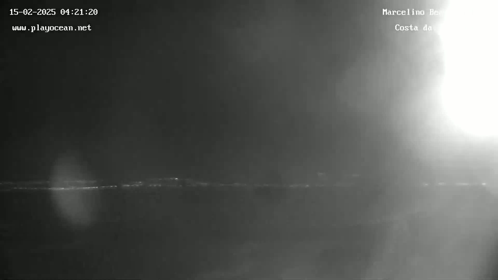 A low-light image shows a dark, hazy or foggy coastline at night.