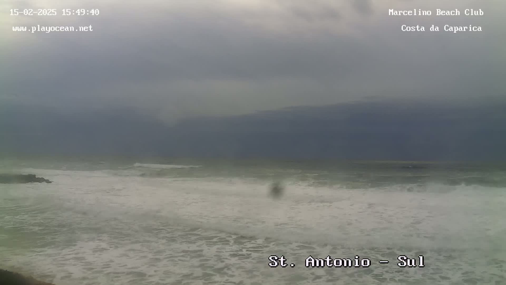 A cloudy, overcast day shows choppy waves crashing on a beach.