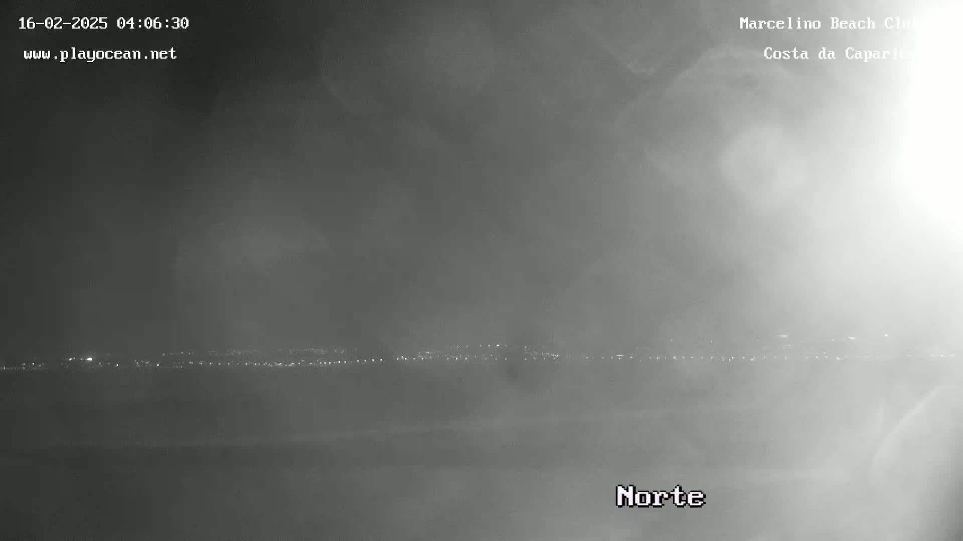A hazy, nighttime view shows a distant line of city lights.