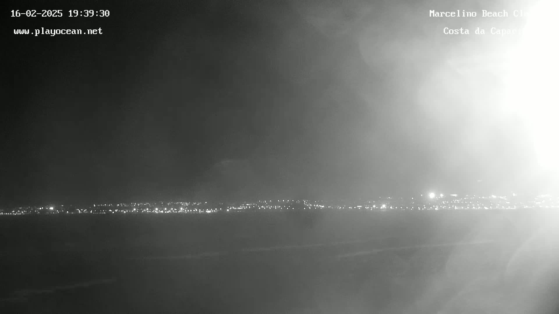 A hazy night scene shows a distant city skyline illuminated by lights.