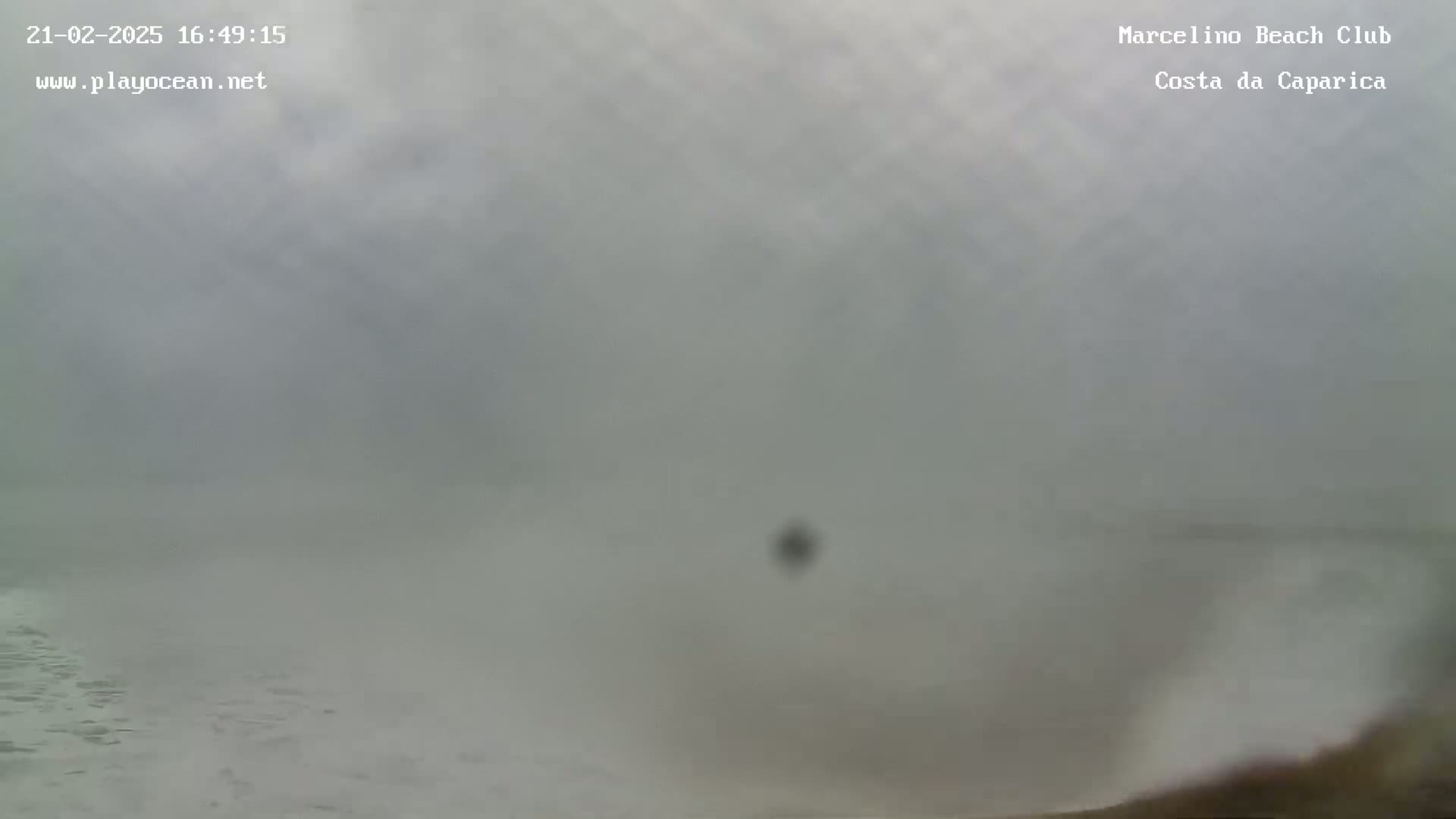 A foggy, overcast day at the ocean shows a mostly obscured view of the water's surface and a small amount of whitecaps.