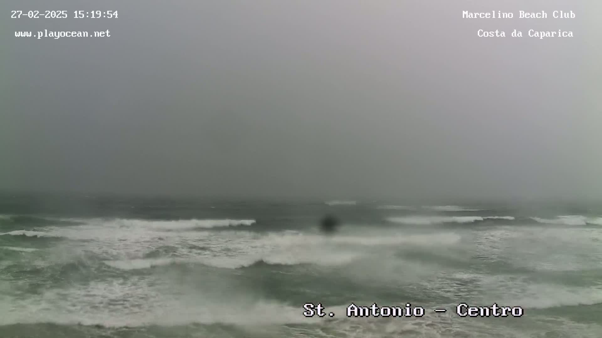 A foggy, overcast day shows a choppy ocean with waves breaking near the shore.