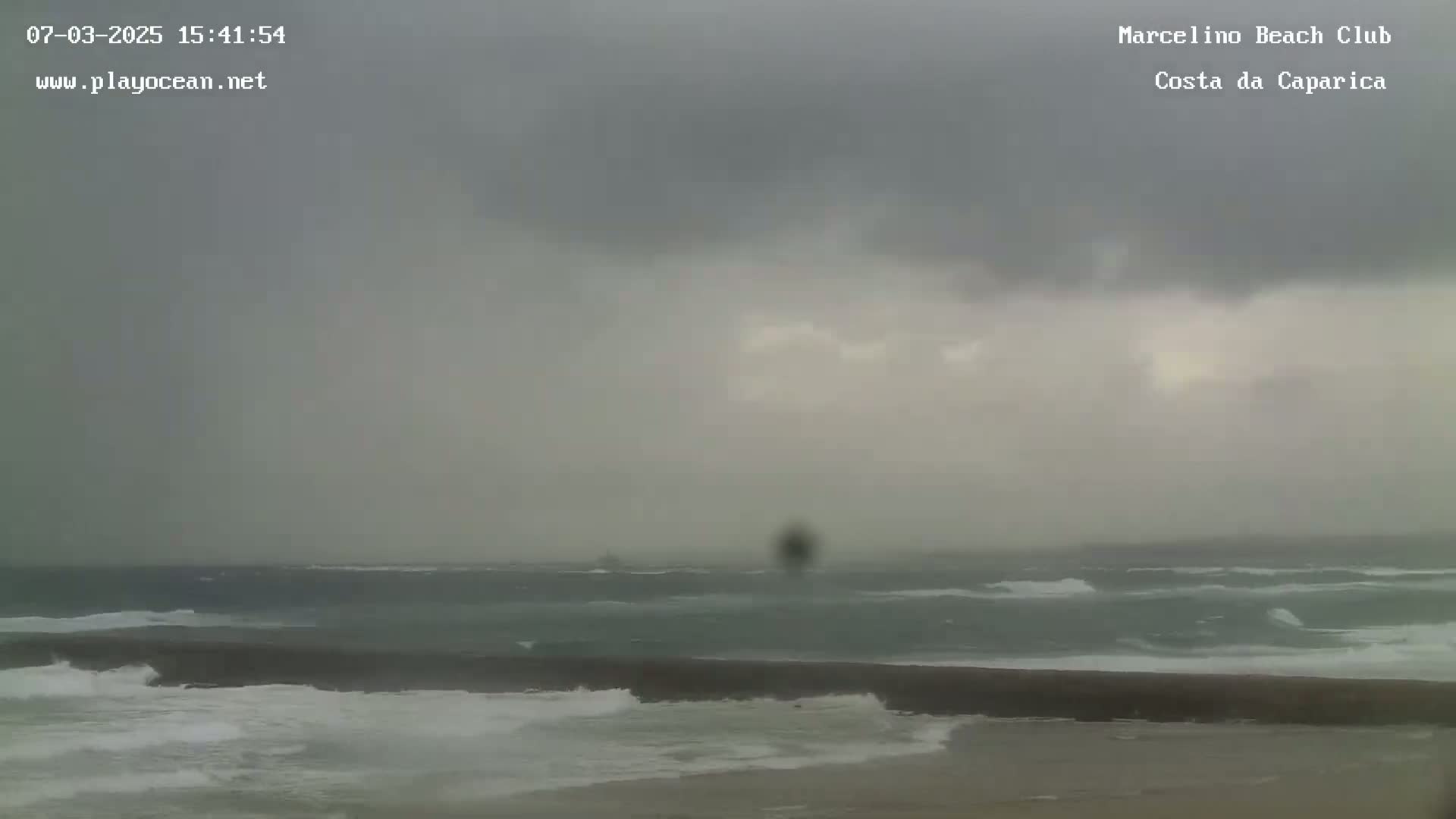 A beach scene shows a choppy ocean under an overcast sky.