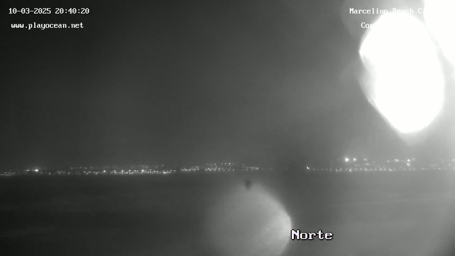 A nighttime, hazy view of a distant city skyline illuminated by lights.
