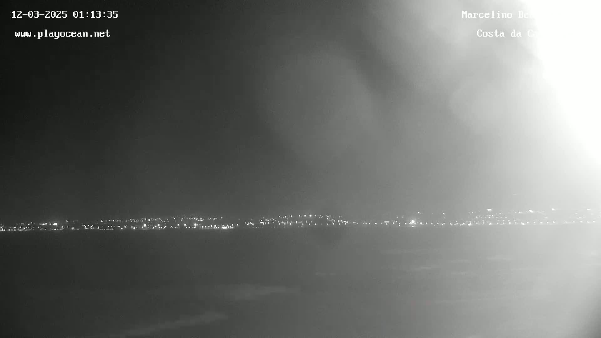 A hazy night scene shows a distant line of city lights.