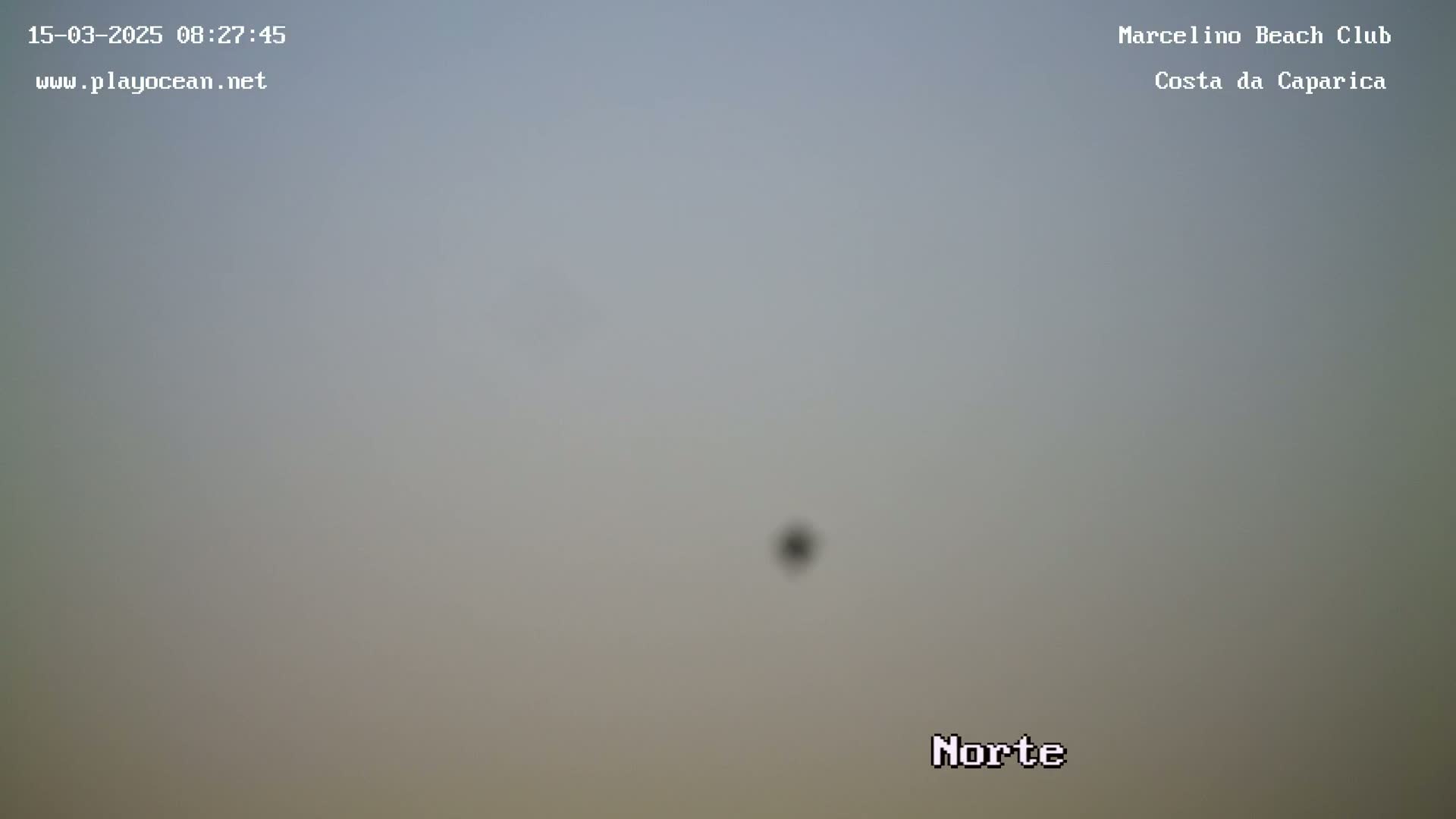 A hazy, overcast sky is visible with a small, indistinct object in the center.
