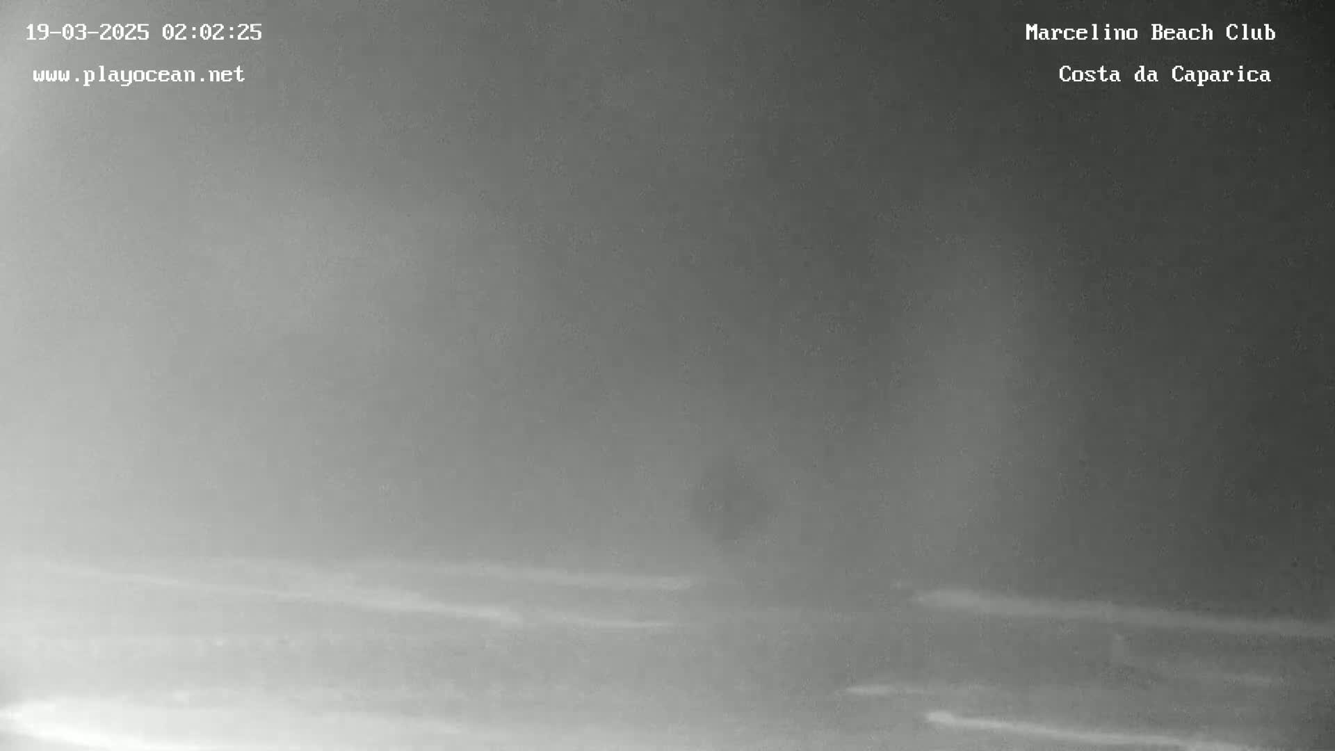 A dark, foggy nighttime scene shows a beach with faint waves.