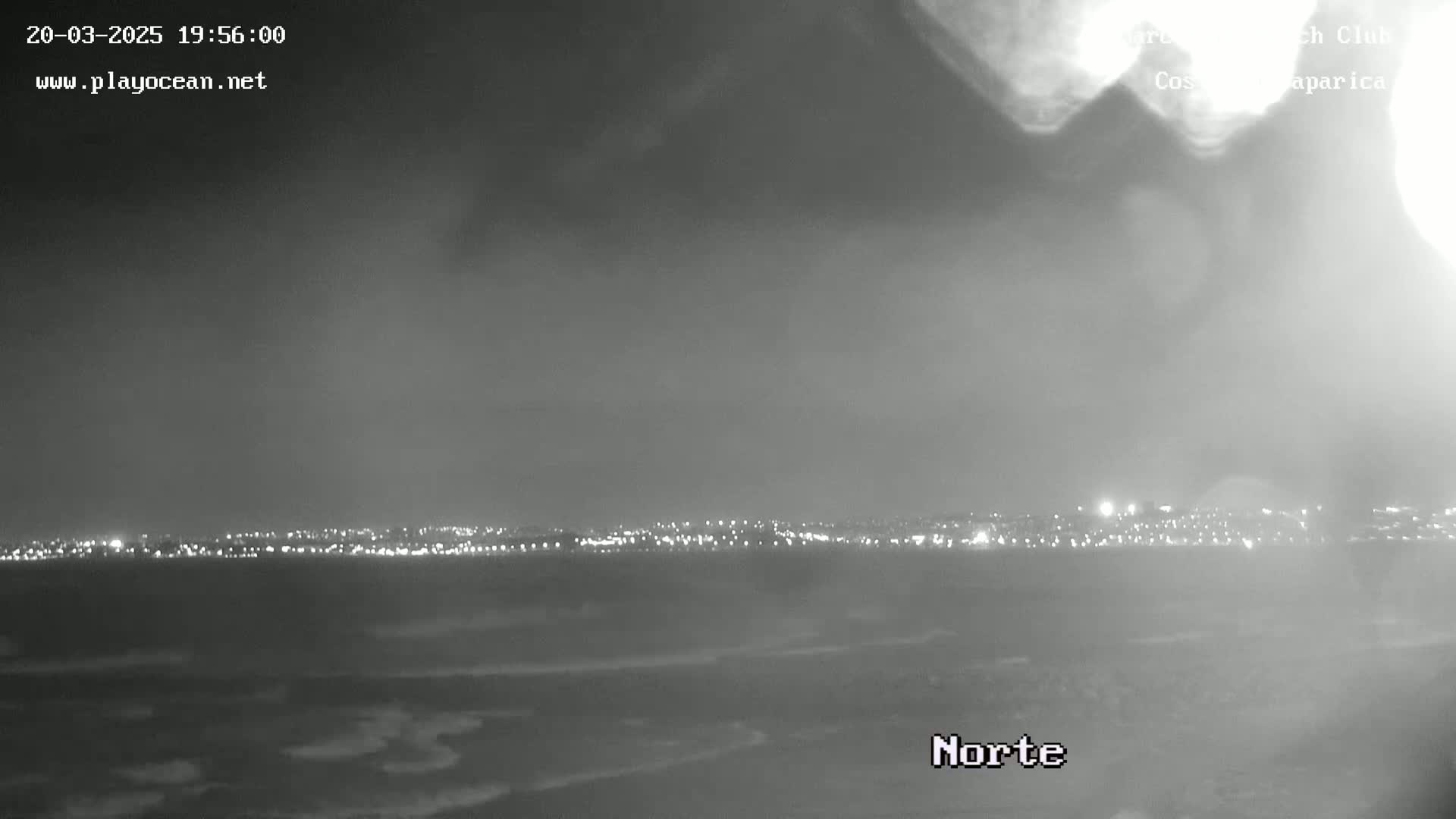 A nighttime, hazy view of a distant city skyline illuminated by lights.
