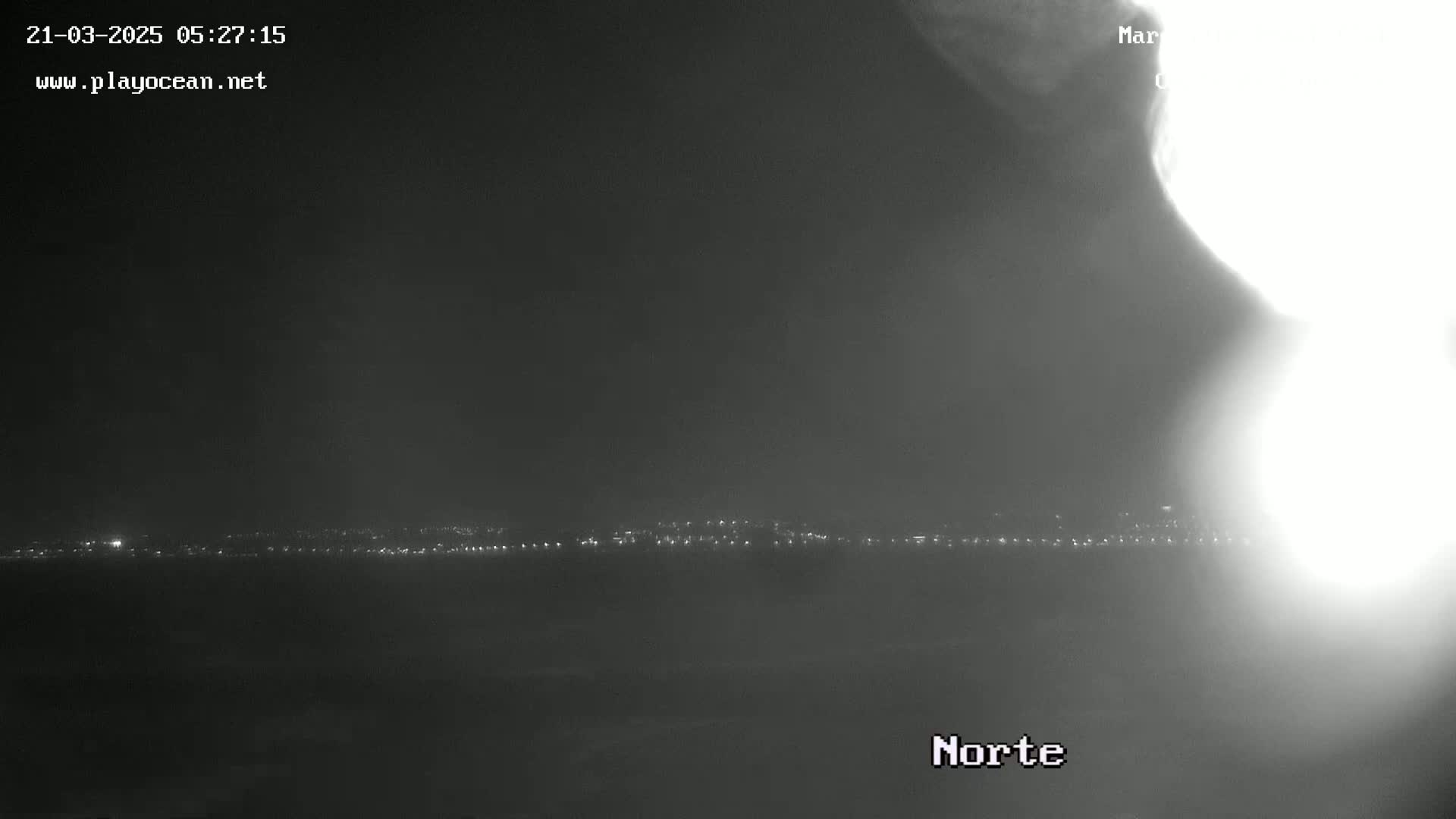 A nighttime, hazy long shot shows a distant city skyline illuminated by faint lights.