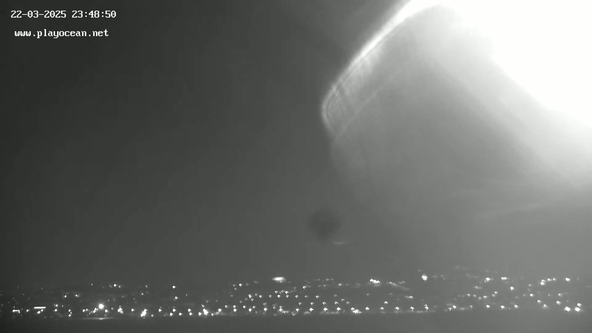 A bright, swirling vortex descends from a dark, stormy sky over a distant, dimly lit city.