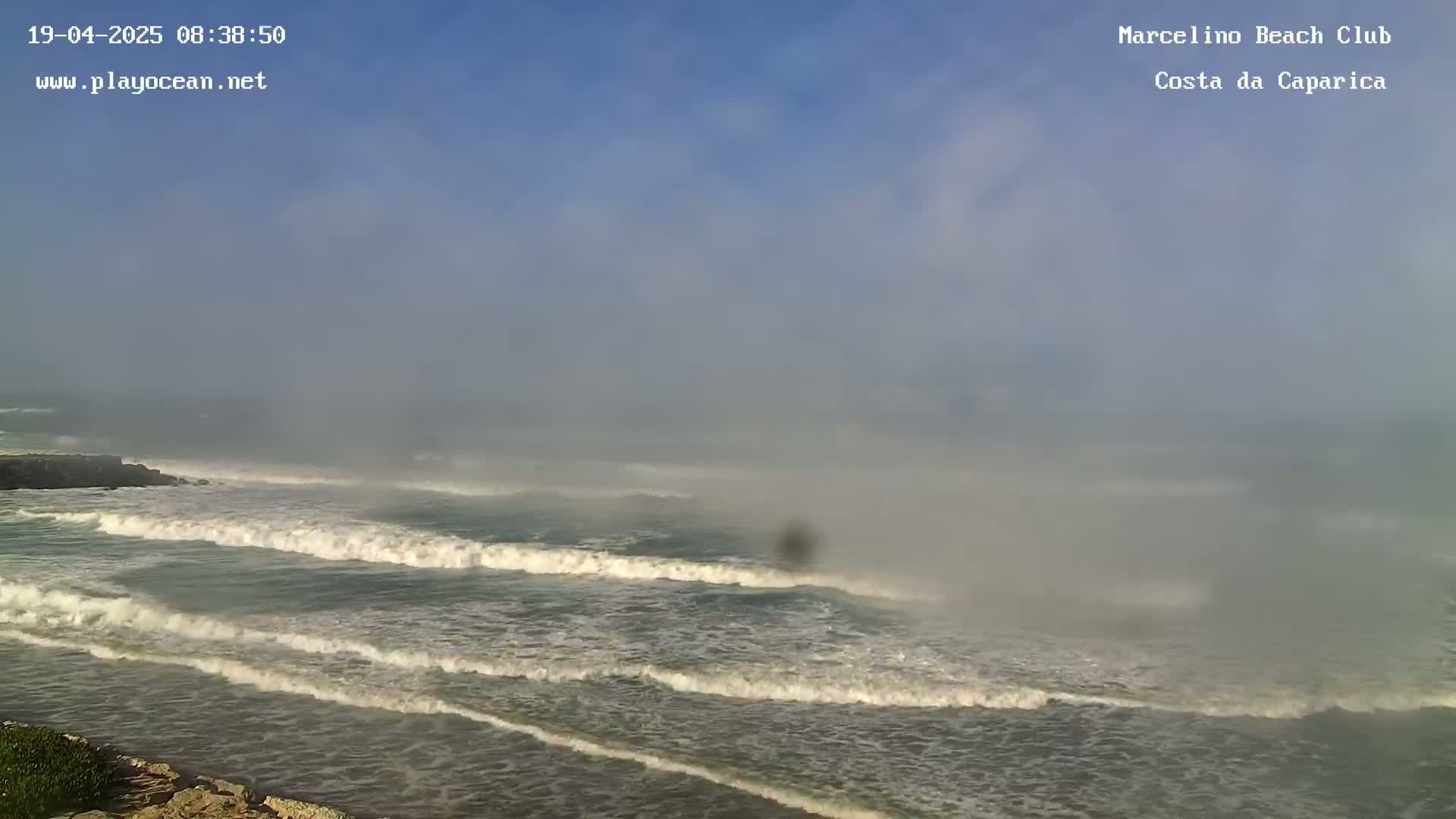 Ocean waves roll onto a foggy shore.