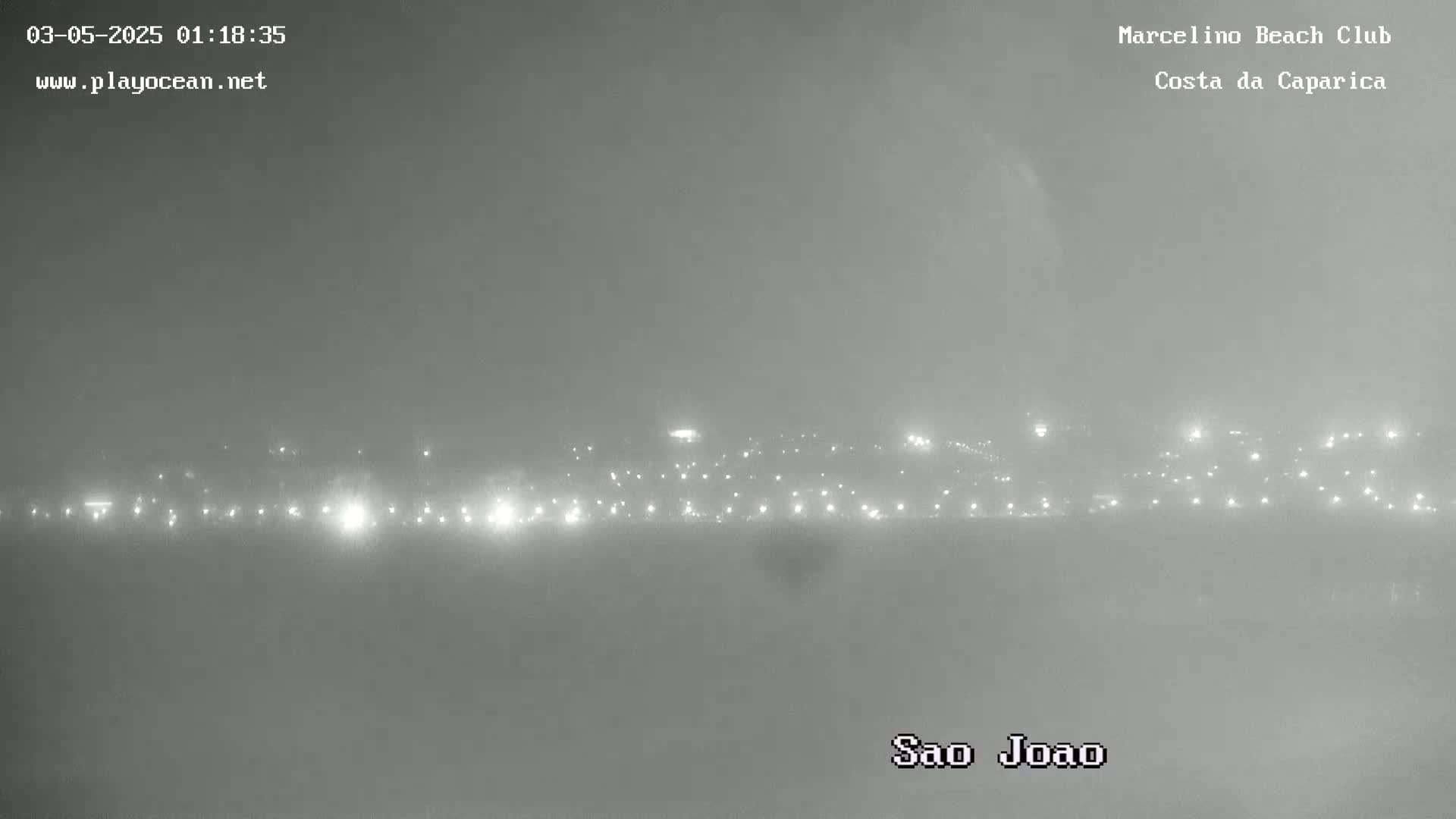A hazy night scene shows a distant line of lights across a flat landscape.