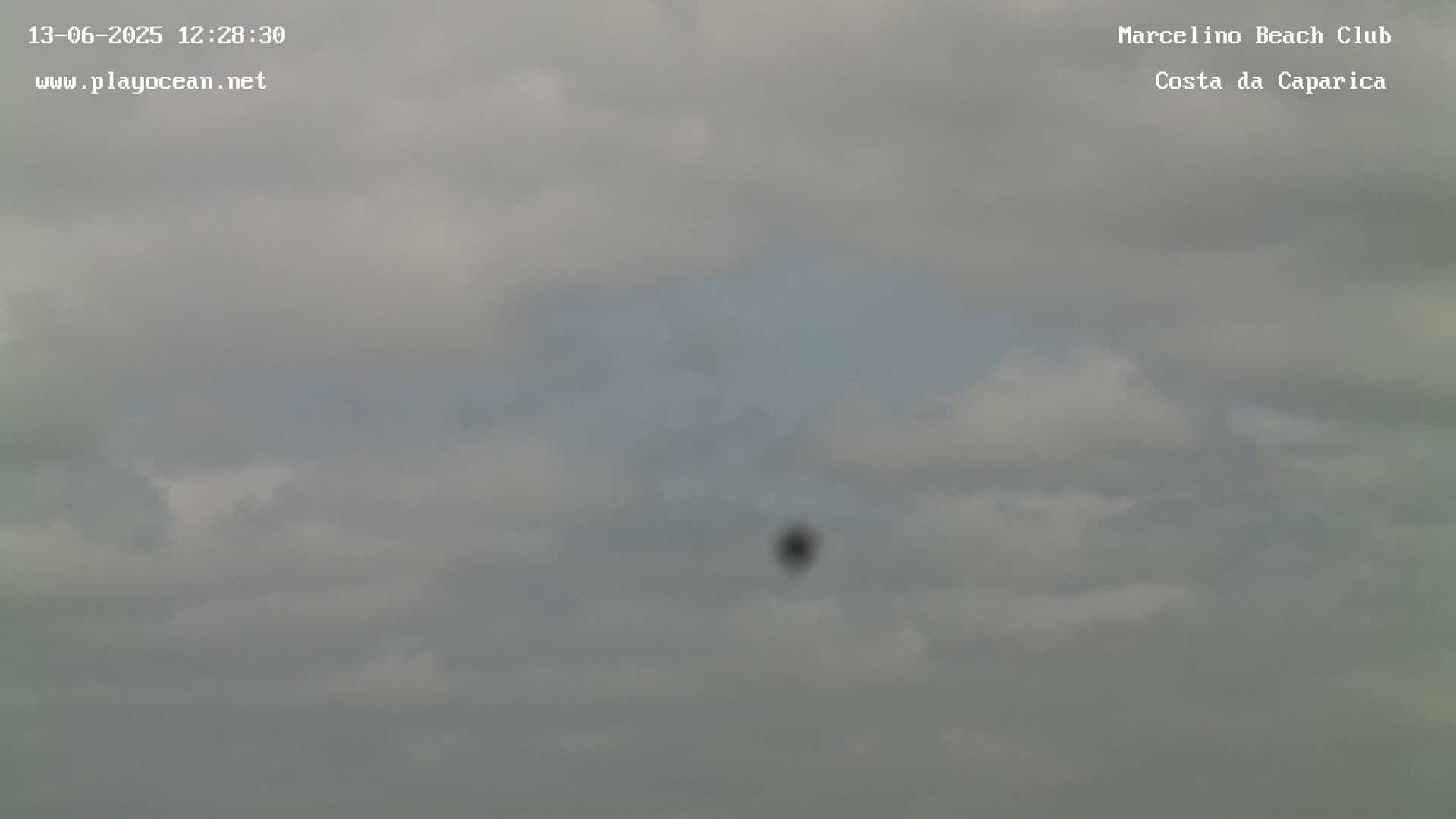A mostly cloudy sky with a small, dark object visible in the distance.