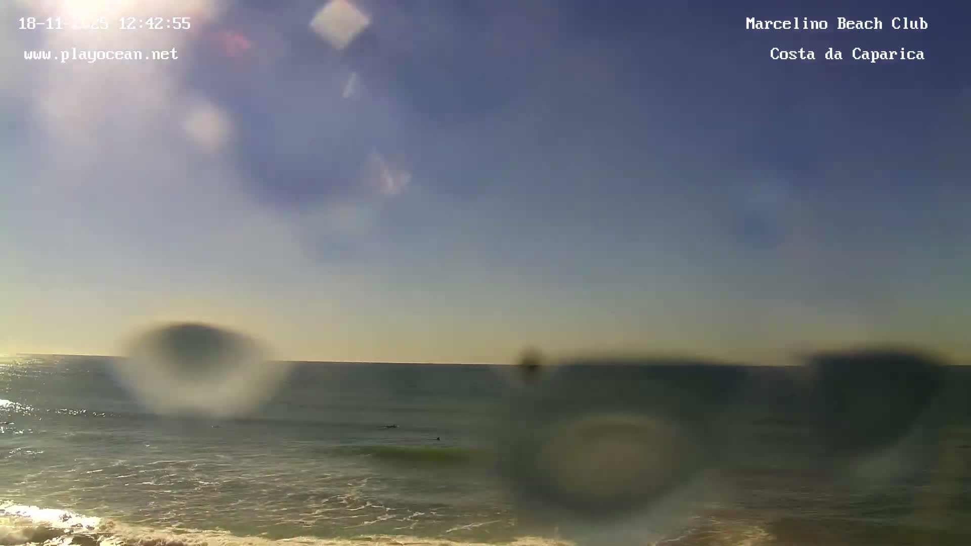 A nighttime, low-light image shows dark ocean waves gently lapping the shore.