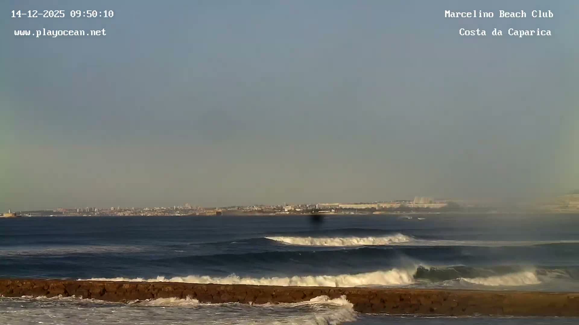A grayscale outdoor scene at night depicts a clear sky above a vast body of water, marked by two distinct bright lights and several horizontal bands of light or wave patterns stretching across its surface.
