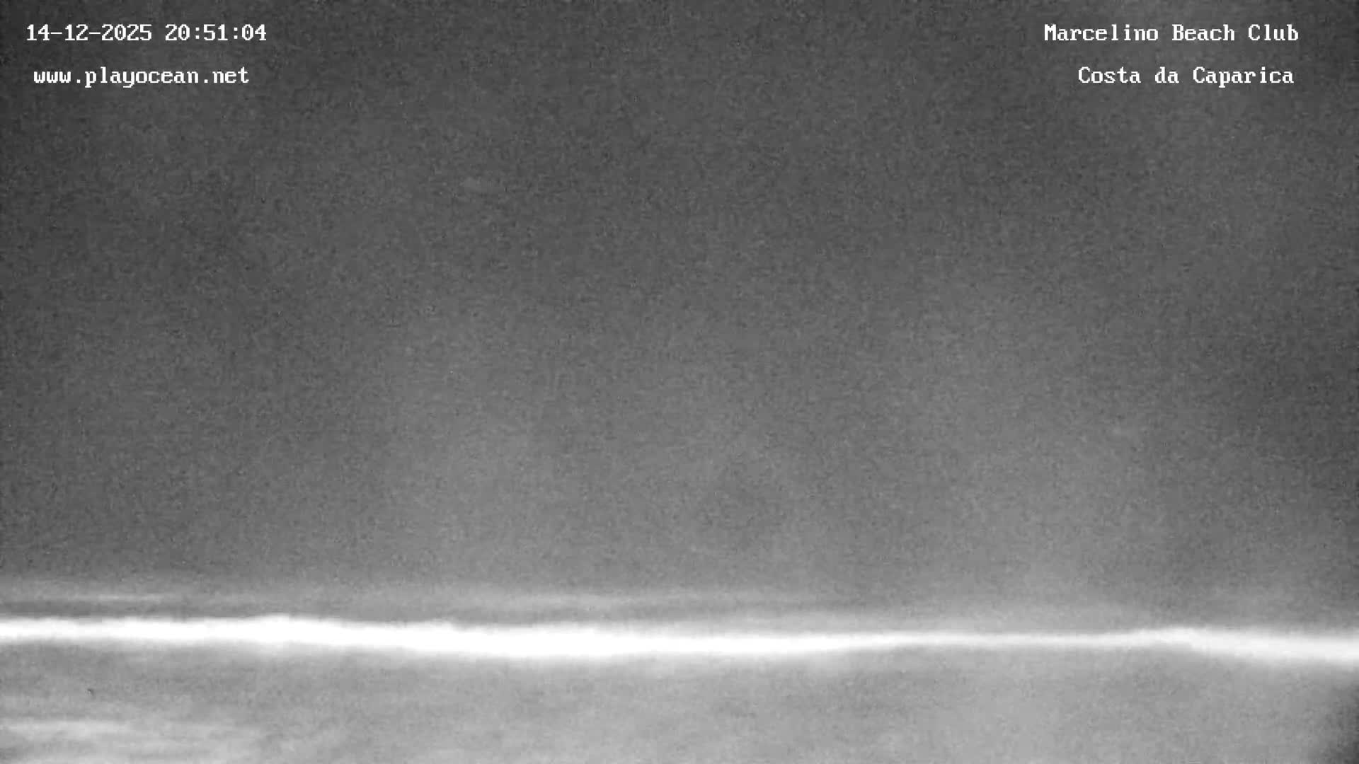 A grayscale outdoor scene at night depicts a clear sky above a vast body of water, marked by two distinct bright lights and several horizontal bands of light or wave patterns stretching across its surface.